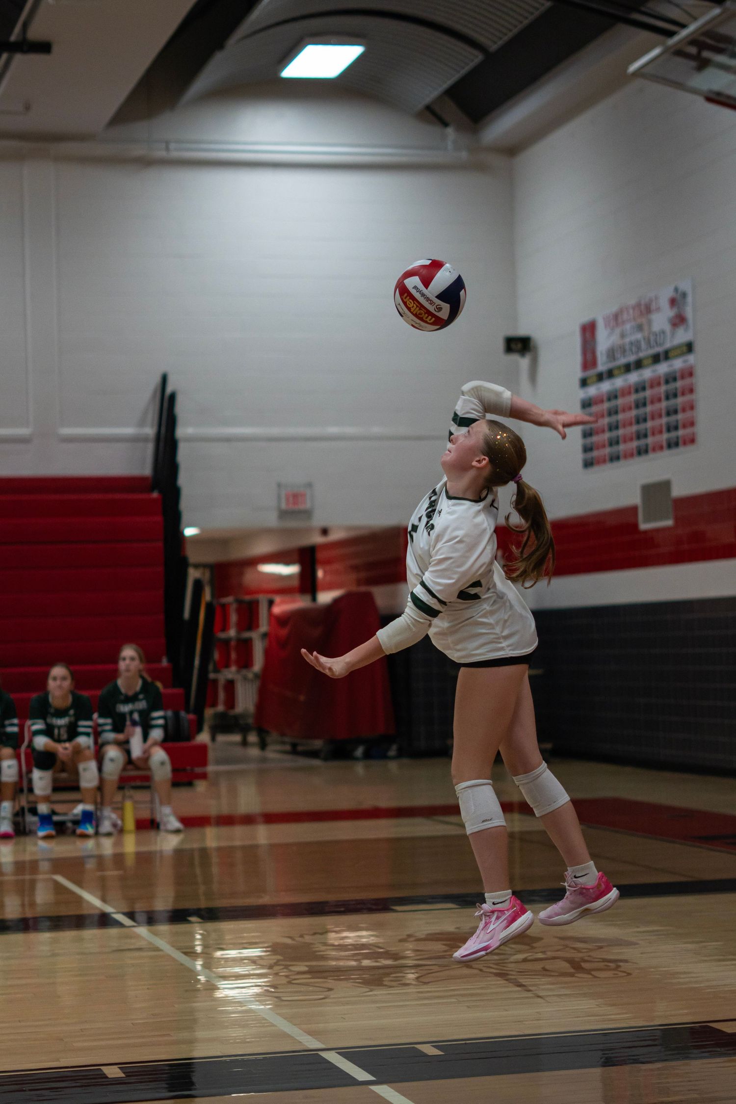 Volleyball player making a diving save on a gymnasium court.