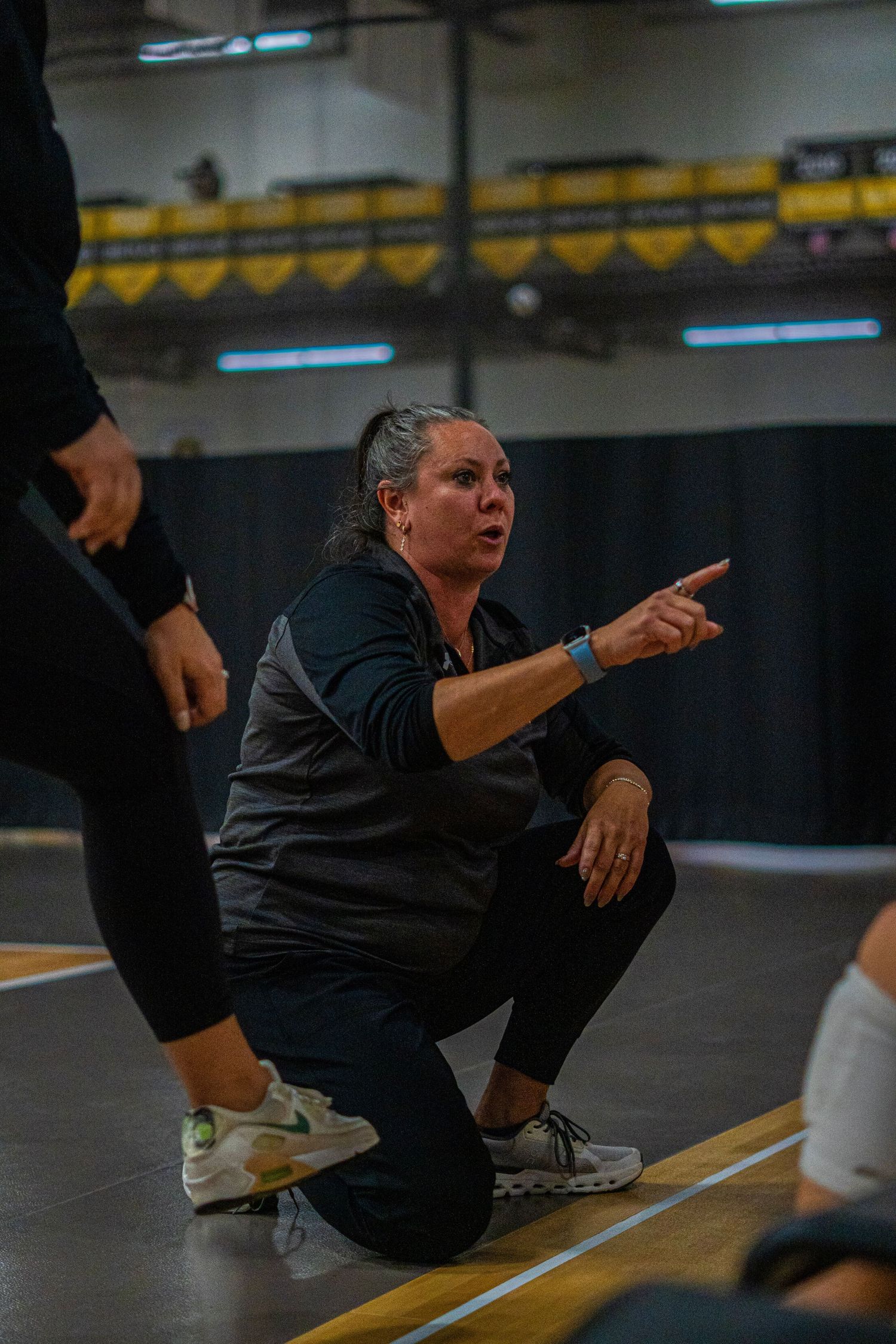Coach demonstrating proper volleyball defensive position during practice session.