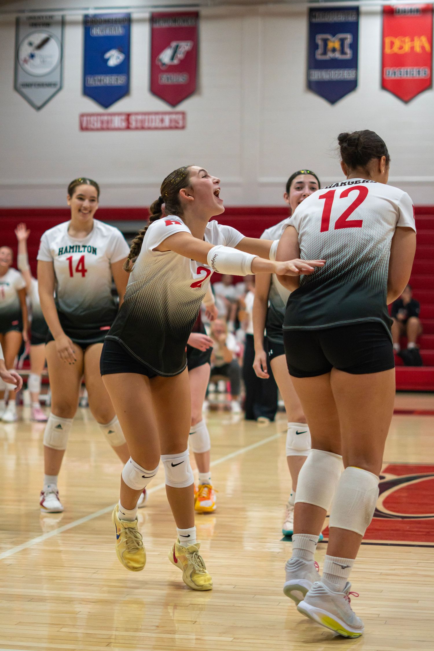 Volleyball players shoving each other excitedly in a gymnasium.