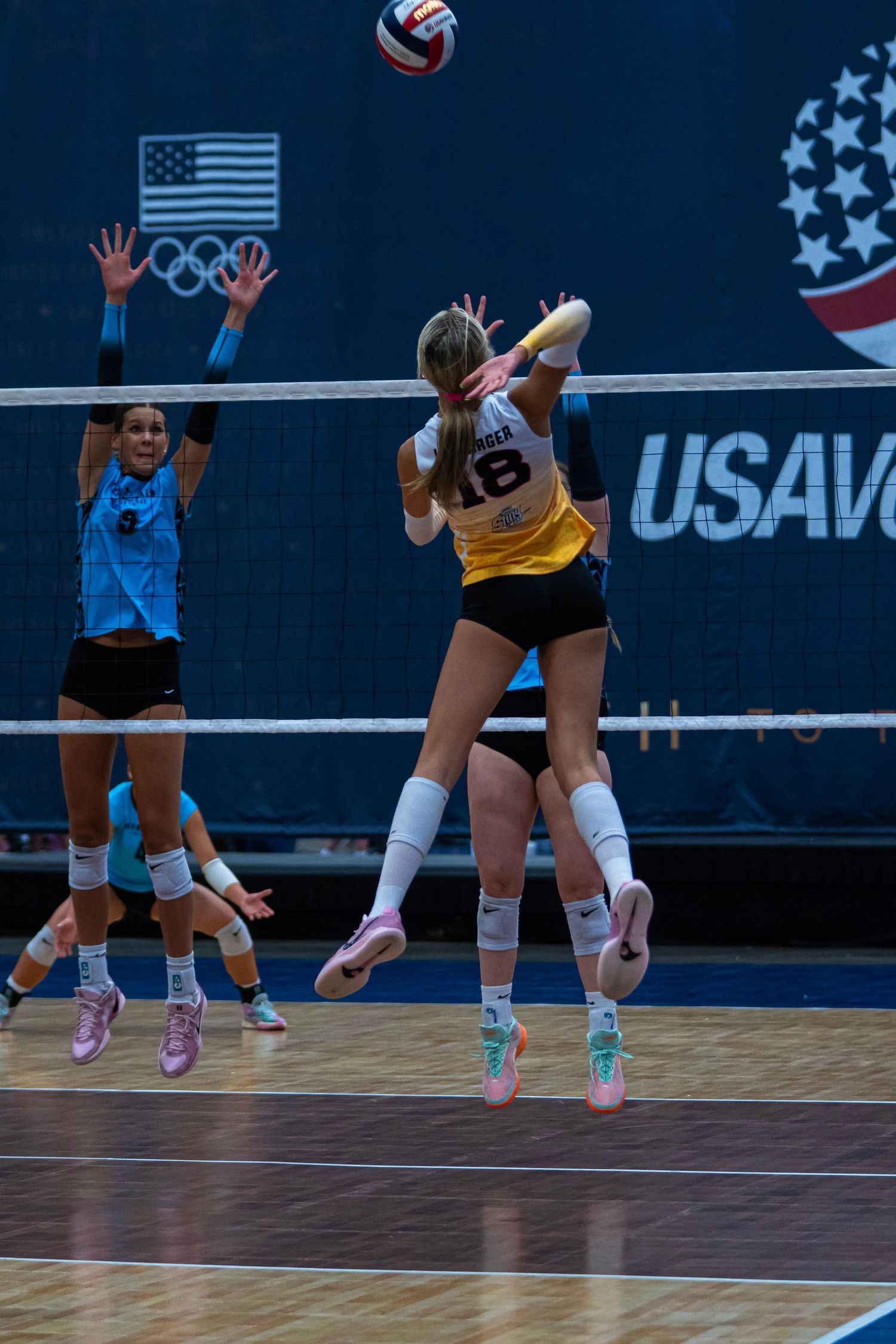 Volleyball players diving and reaching for a low ball during a match.