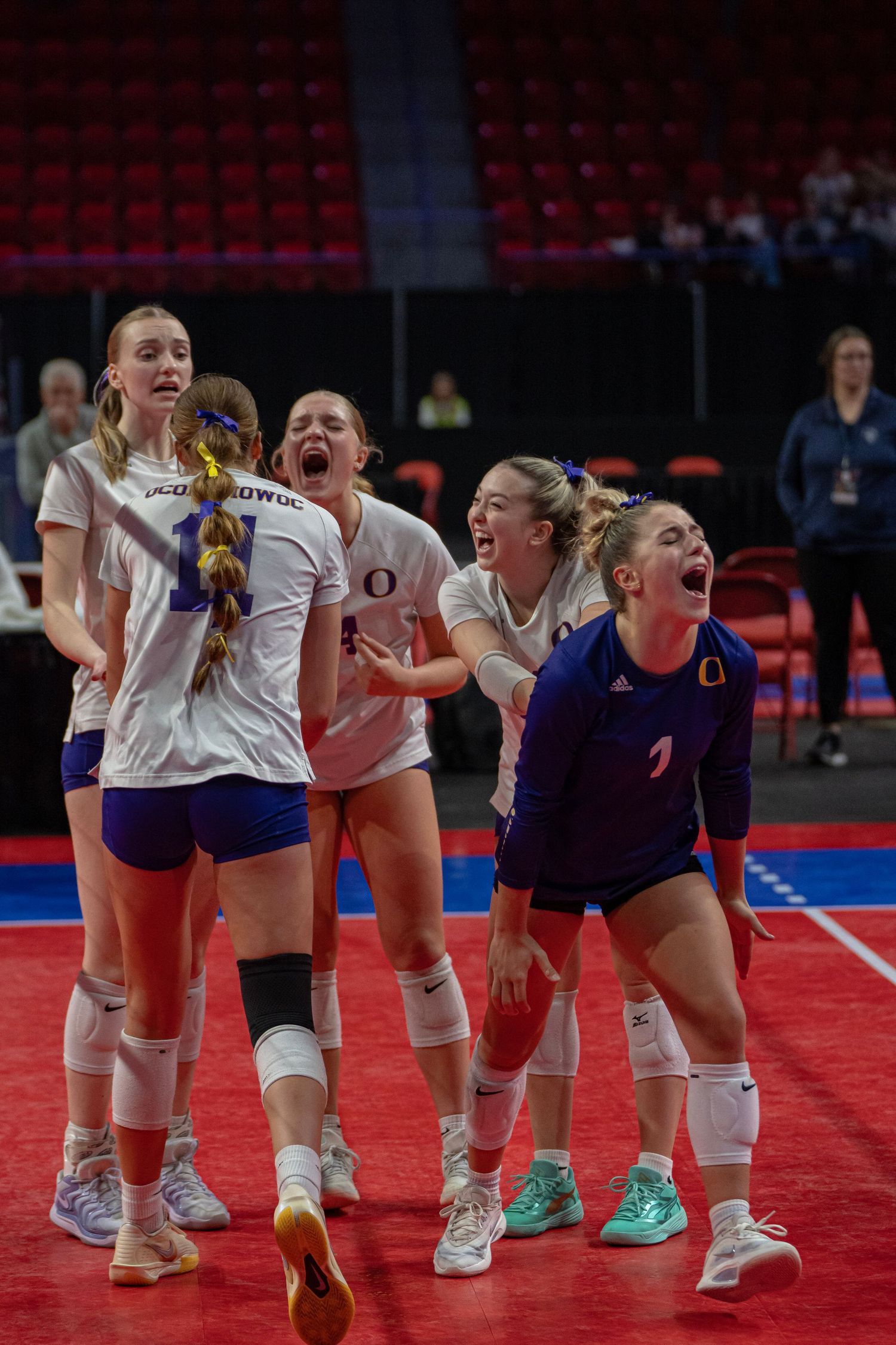 Female volleyball players celebrate on court by performing a synchronized dance move during a match.