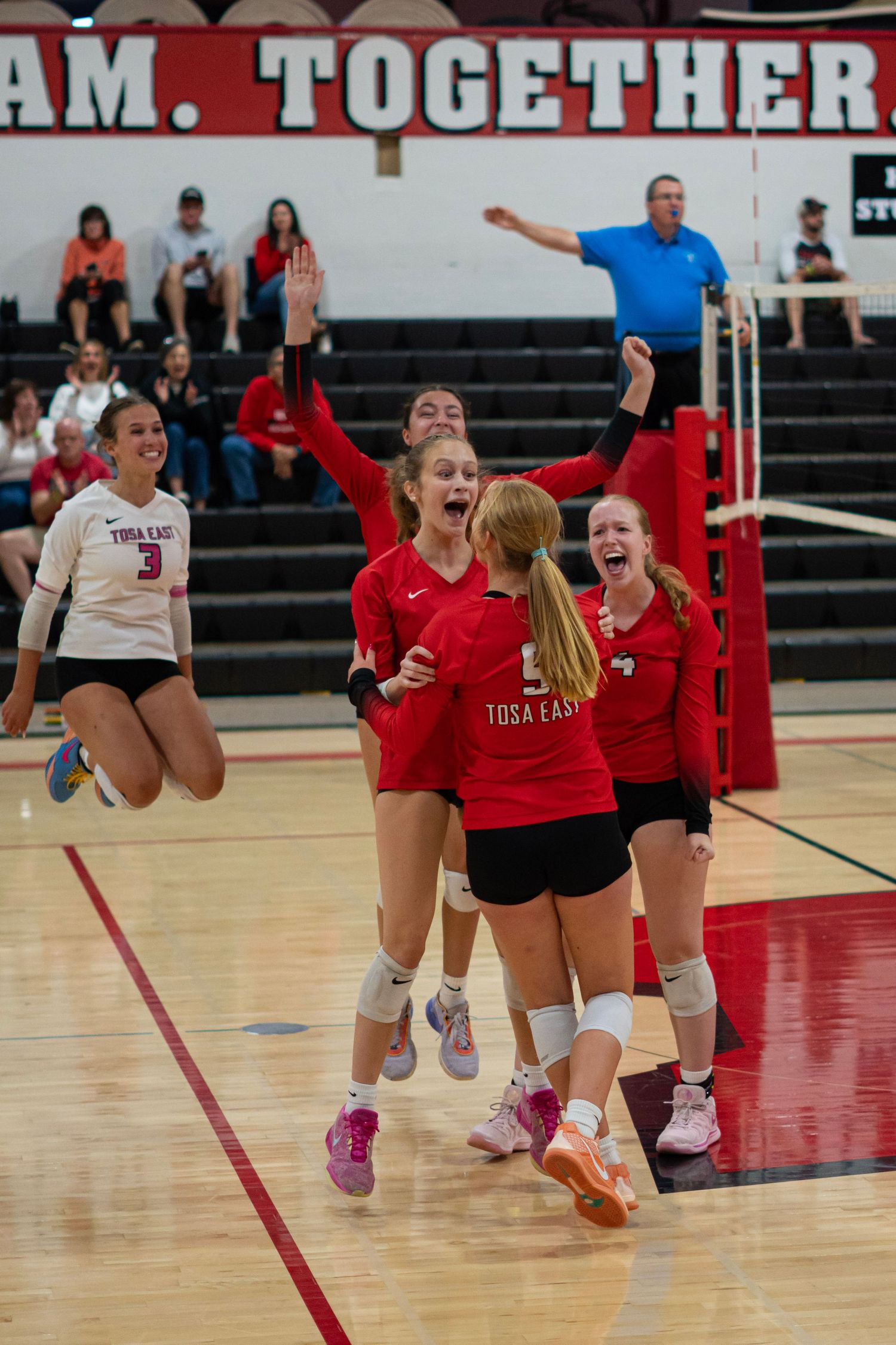 Players celebrating a point with enthusiasm on an indoor volleyball court.