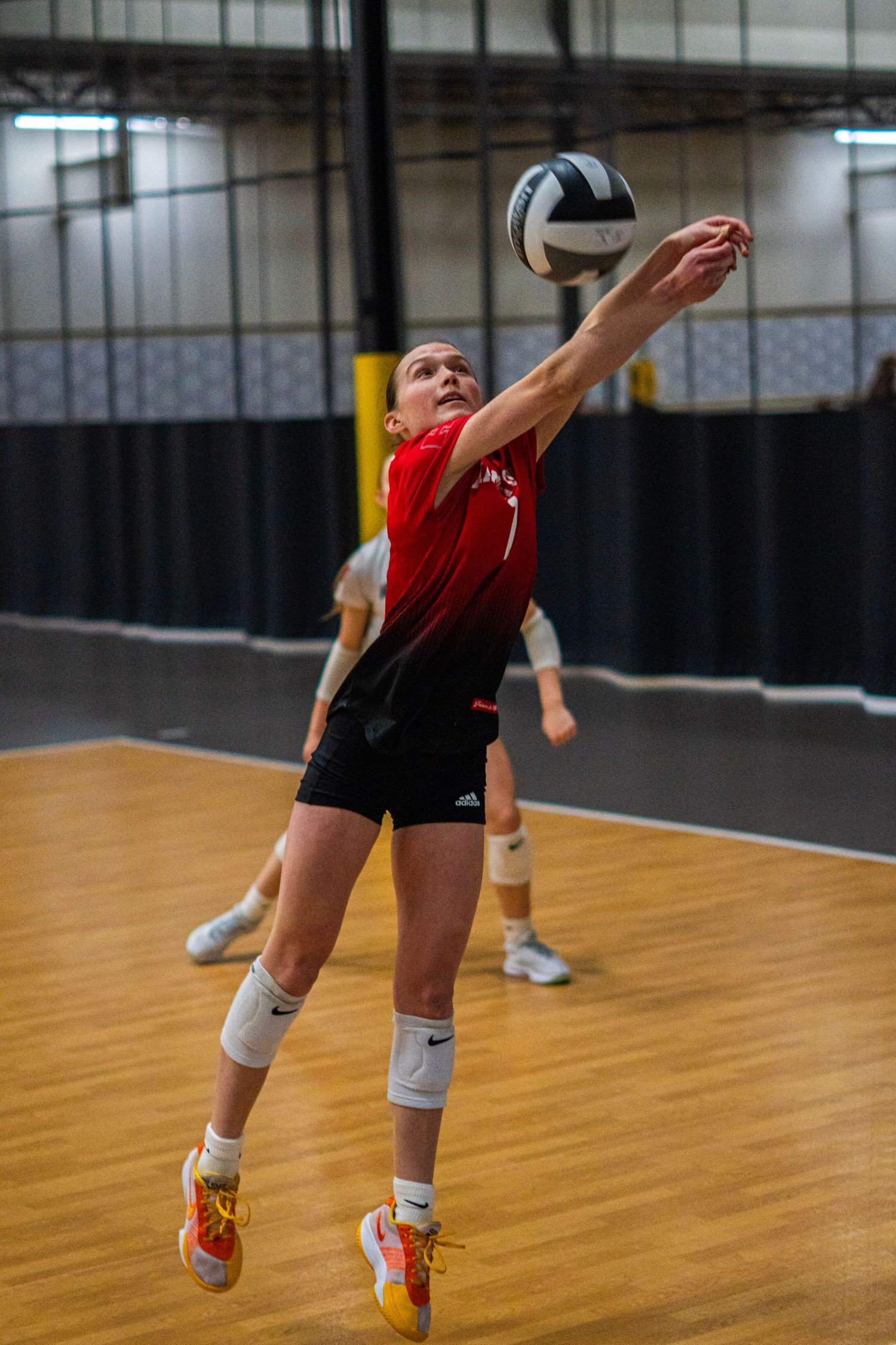Volleyball player making diving save attempt on wooden court during match.