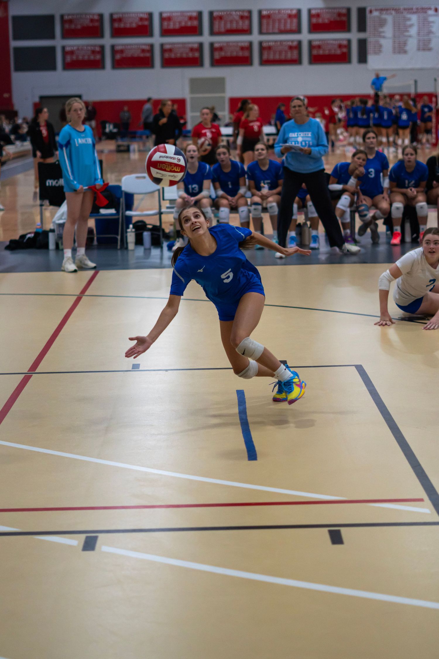 Volleyball players executing diving defensive moves during a match.