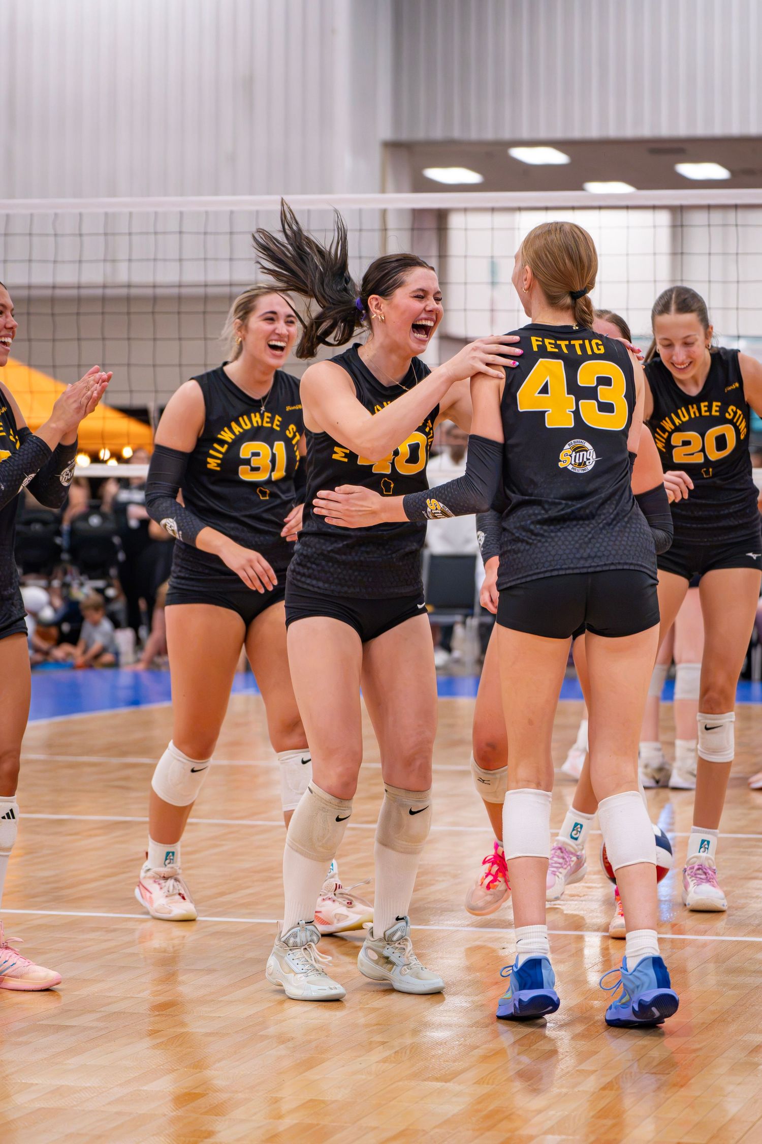 Milwaukee State volleyball players celebrate together on the court during a competitive match.