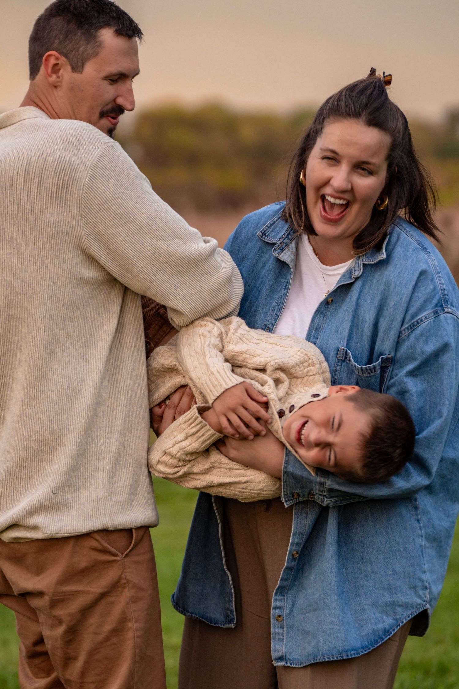 A playful couple shares joyful moments together outdoors during a casual photo session in nature.