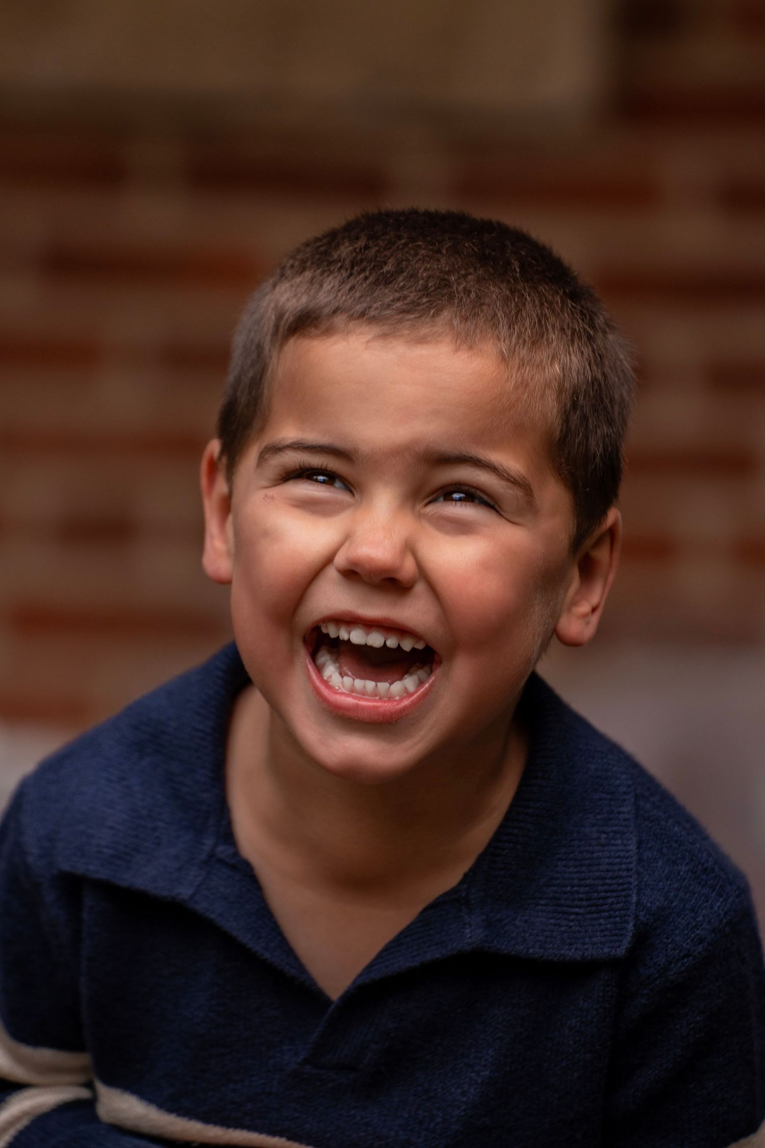 A sequence of five candid expressions showing joyful laughter and genuine emotion while wearing a navy blue sweater.