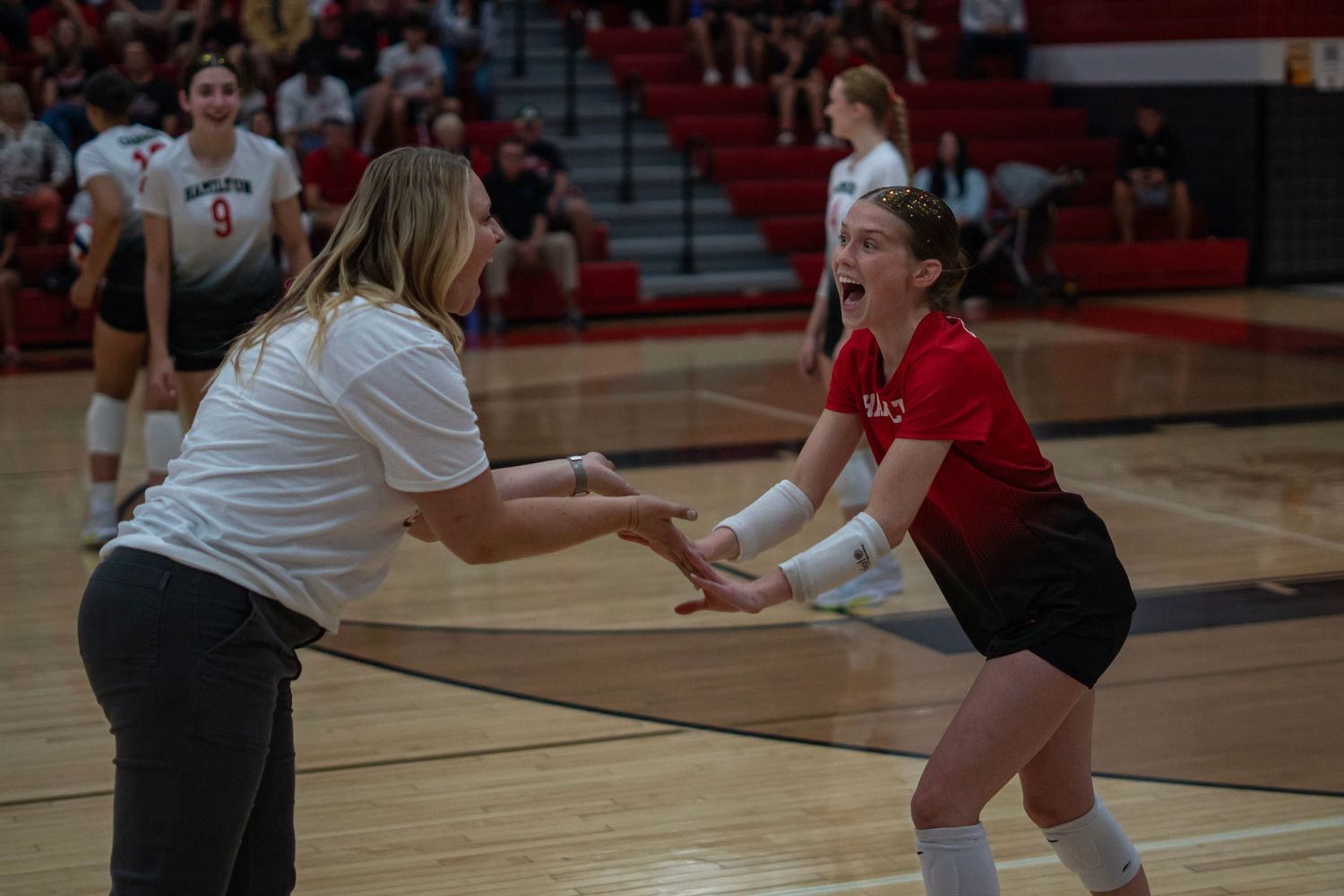 Players reaching for the ball during a competitive indoor volleyball match.