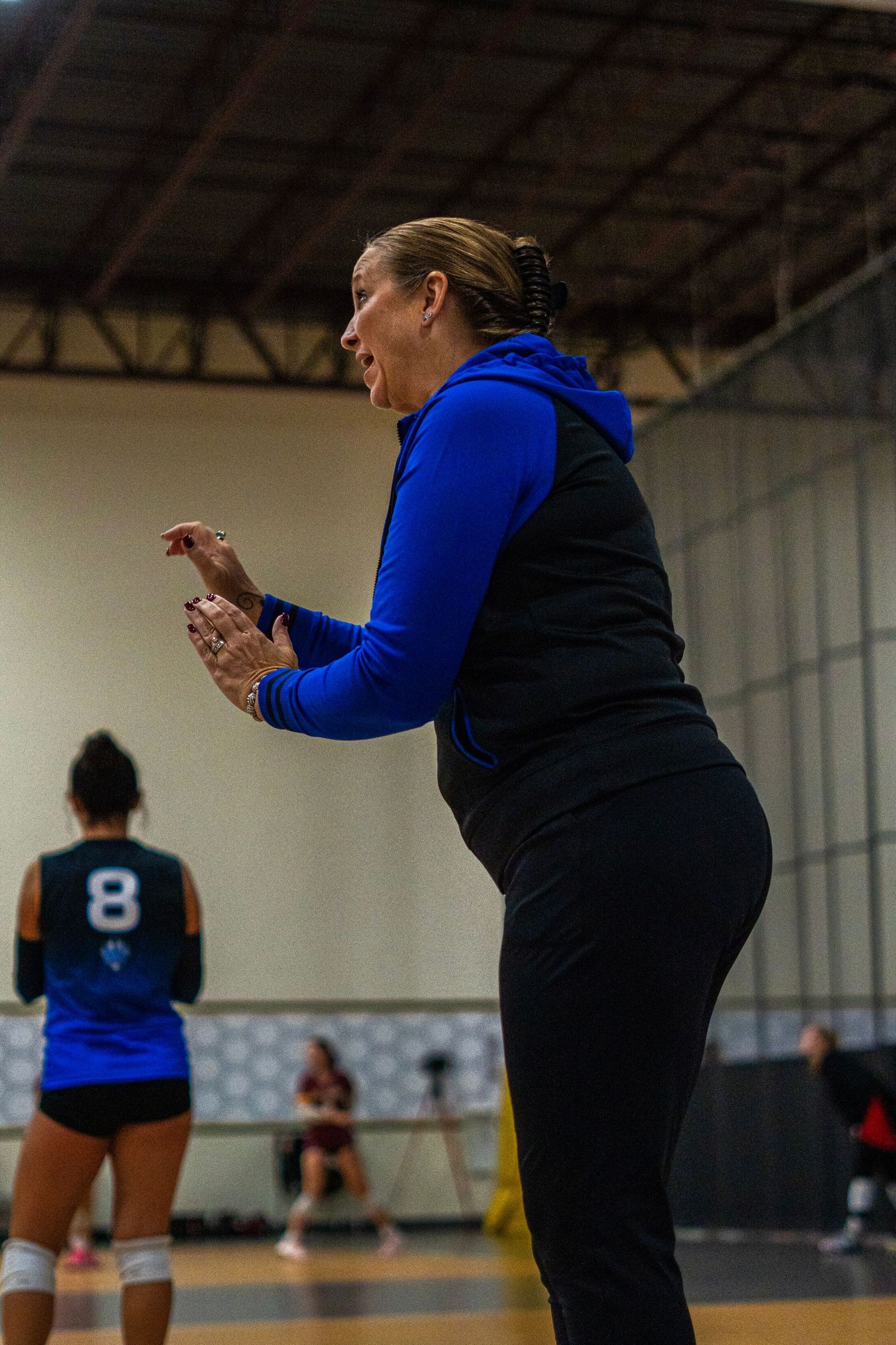 Players practicing volleyball drills in a gymnasium with blue uniforms.
