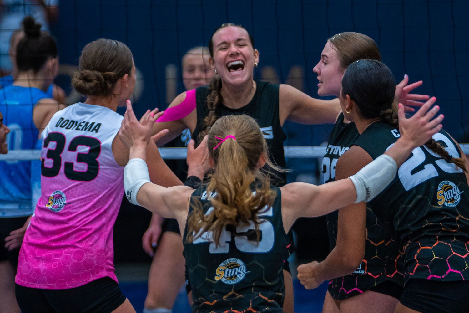 Volleyball team members celebrate a point with excitement on the court.
