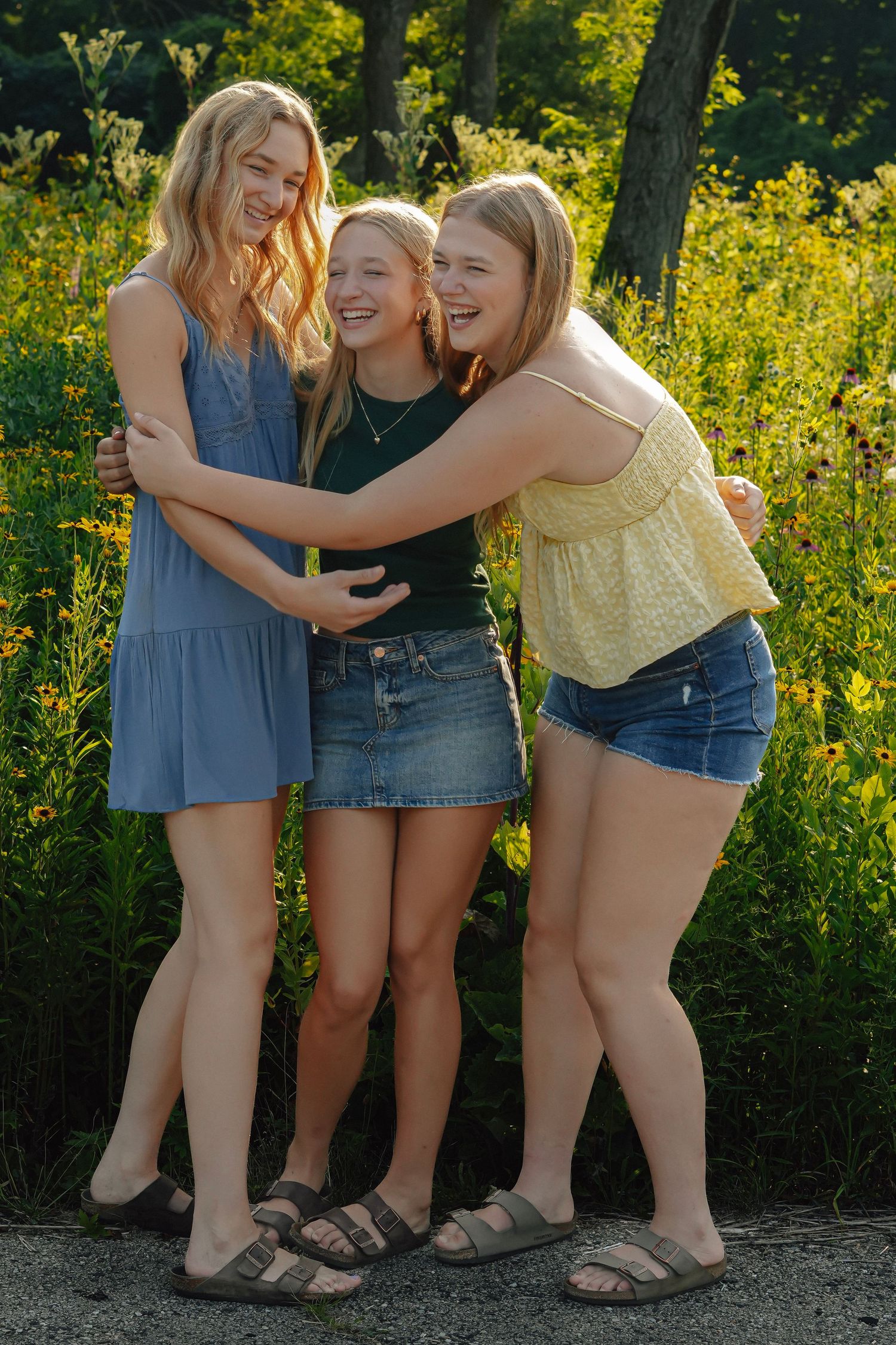 Friends share joyful moments together outdoors against a backdrop of vibrant yellow wildflowers on a sunny day.