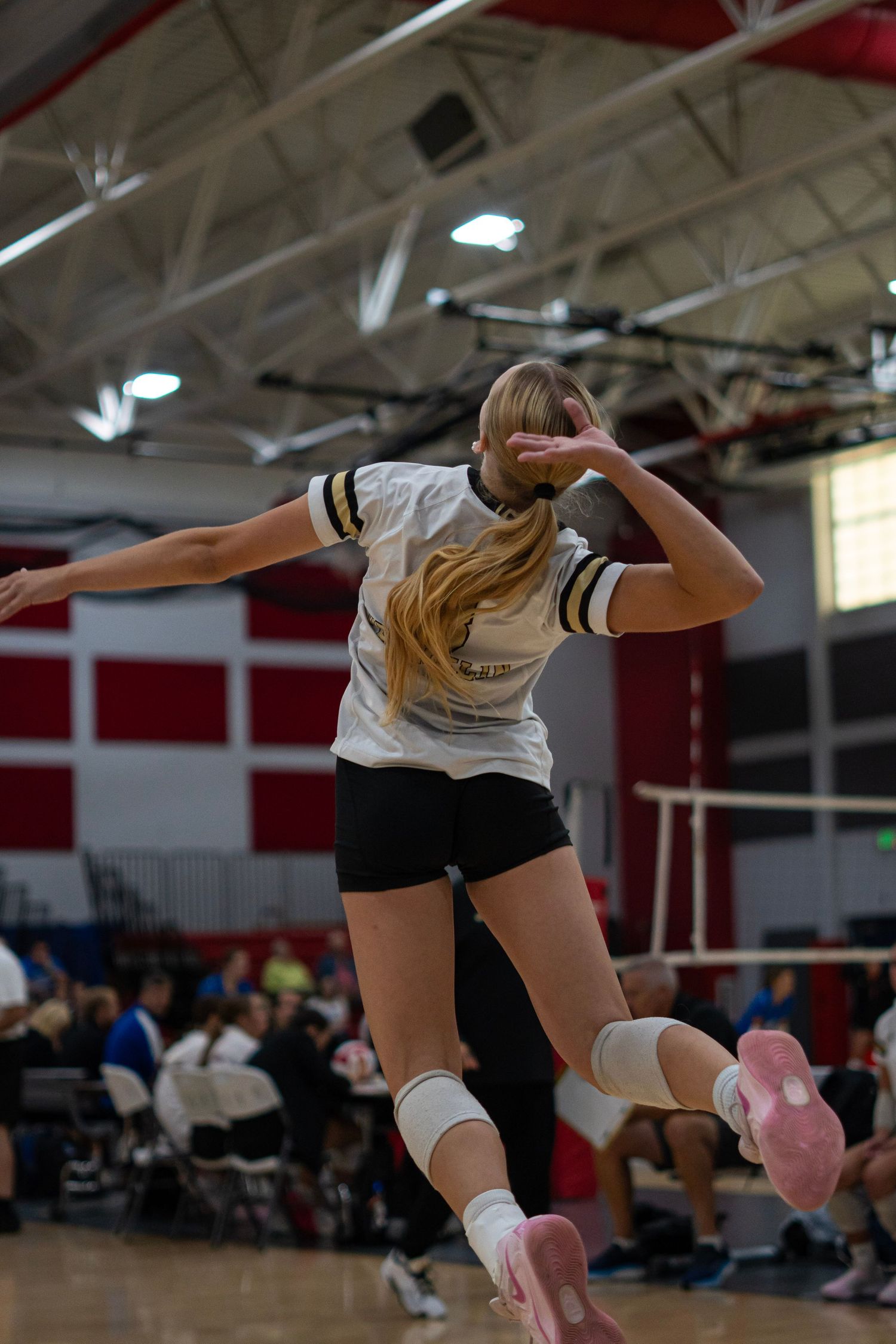 Volleyball players diving and stretching to save a ball during an intense game.