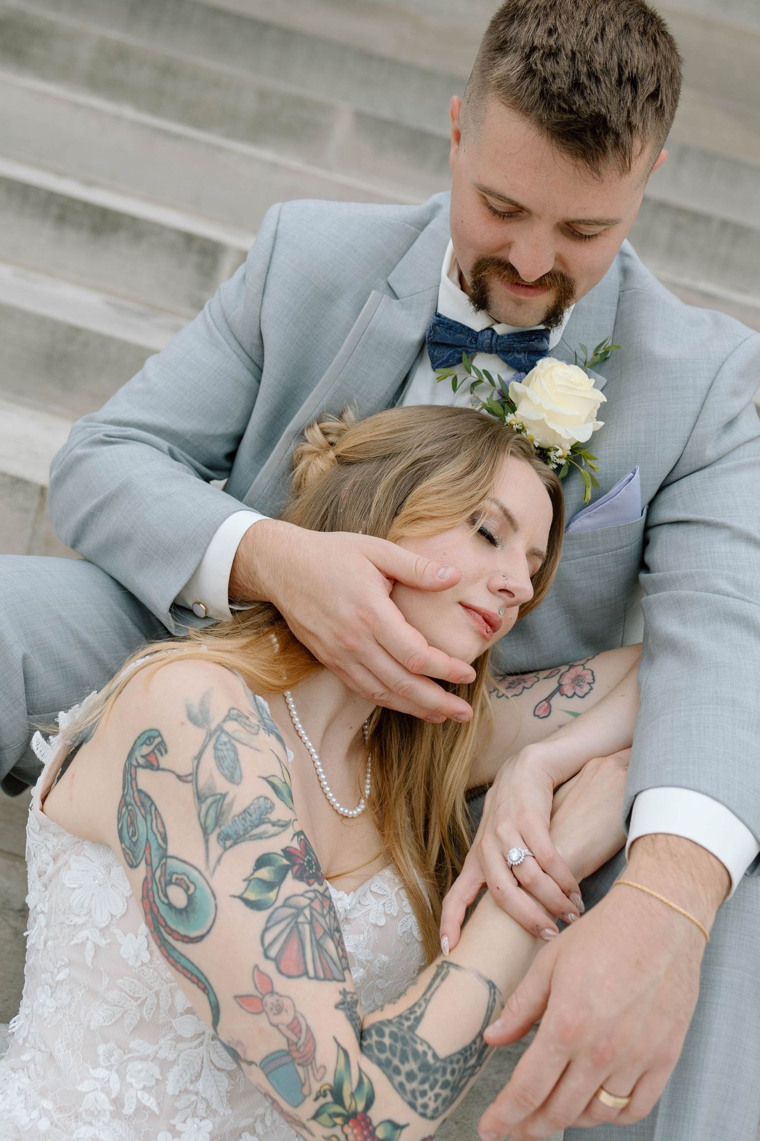 Artistic wedding portraits showing tattooed couple in intimate poses wearing gray suit and white dress.