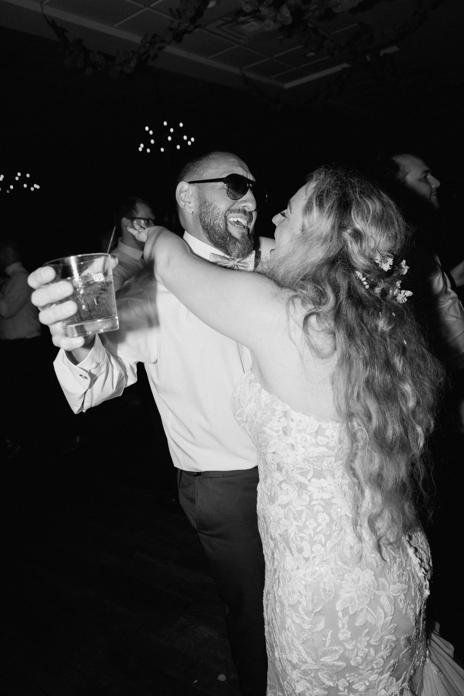 Wedding couple dances together in dark reception venue with dramatic lighting.