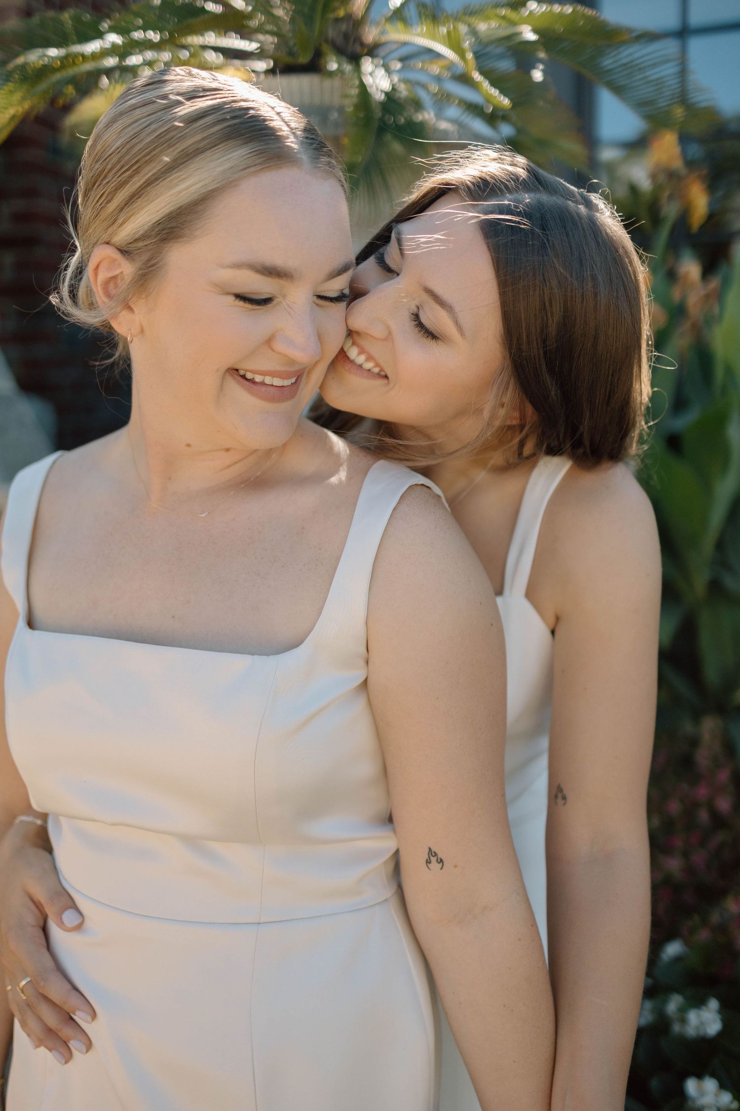 Couple in matching white outfits share affectionate moments against a tropical backdrop.