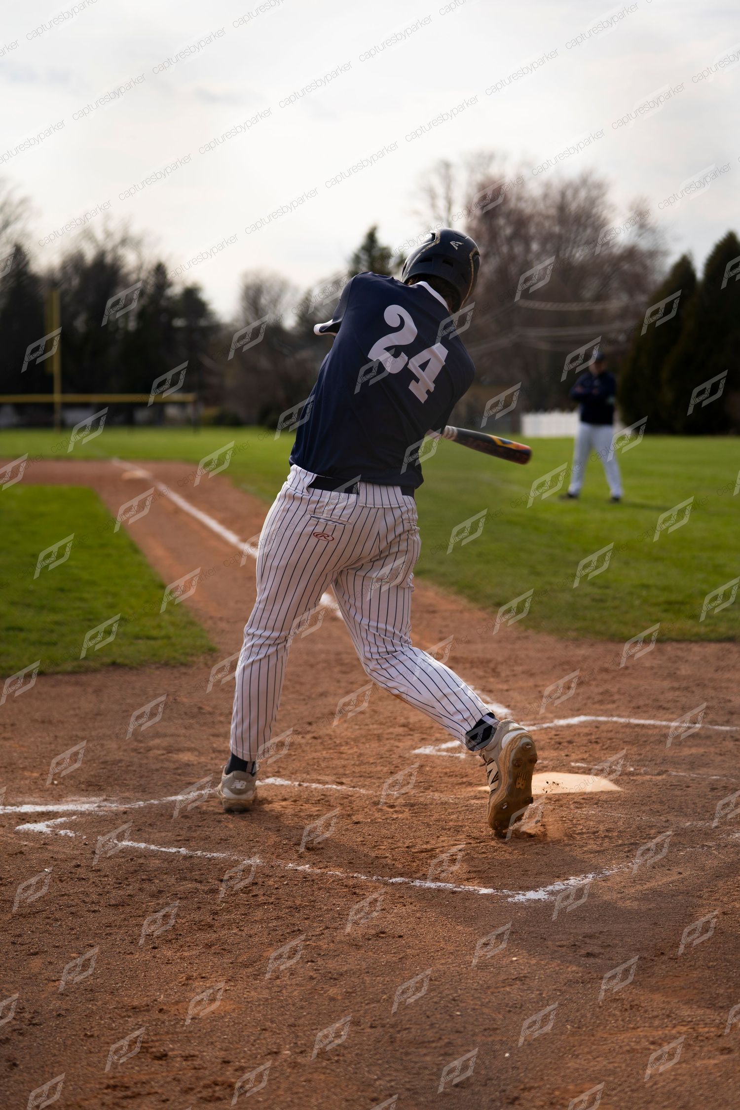 Baseball player #24 in navy uniform swings bat at home plate during a game.