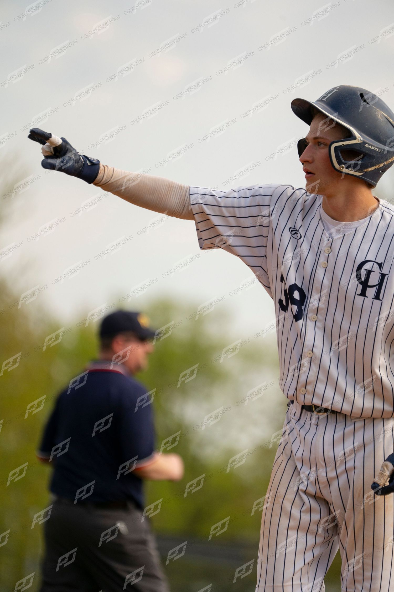Baseball player in pinstripe uniform celebrates and points after a hit during a game.