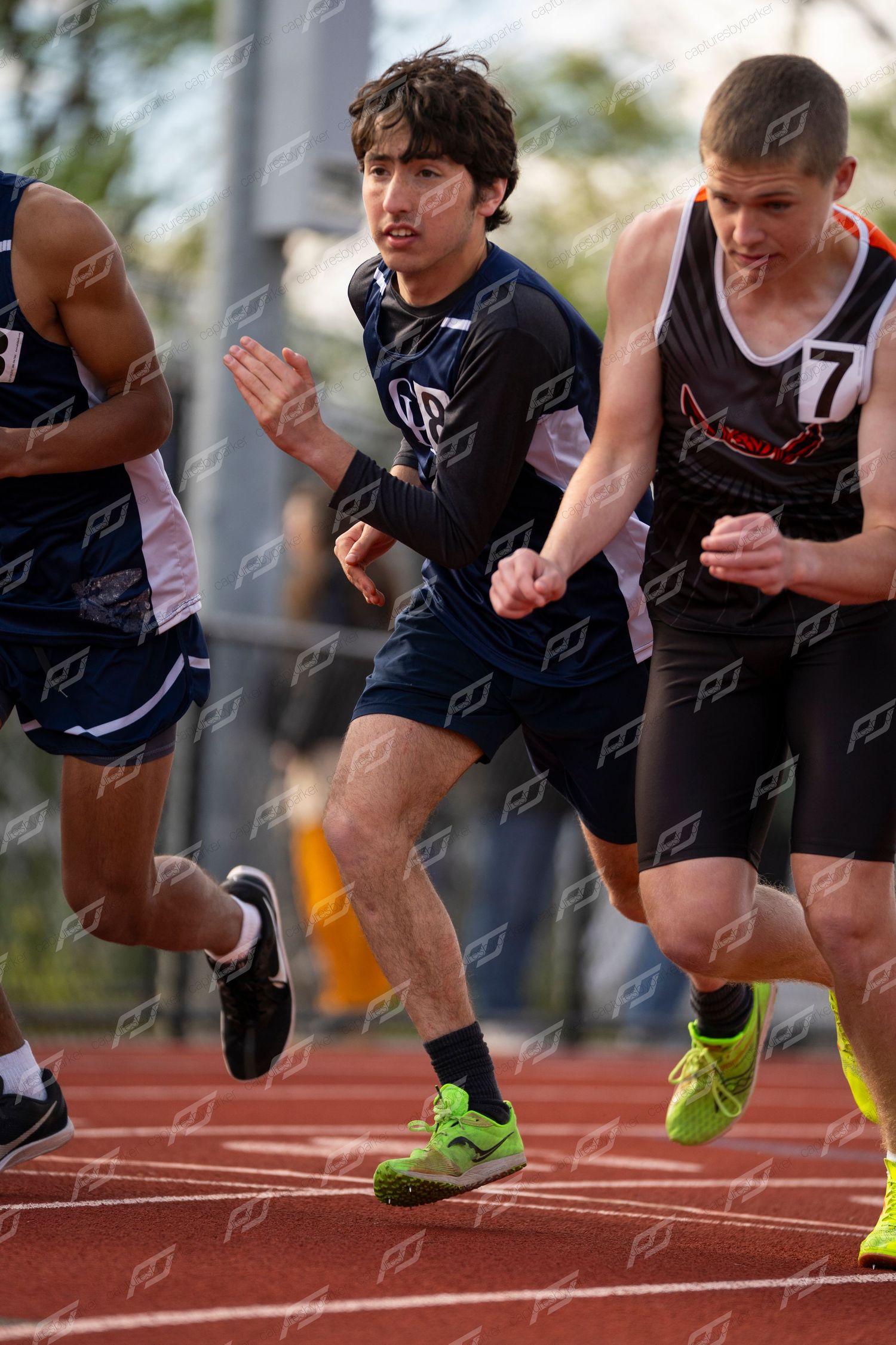 Male track athletes sprint from the starting line during a competitive race.