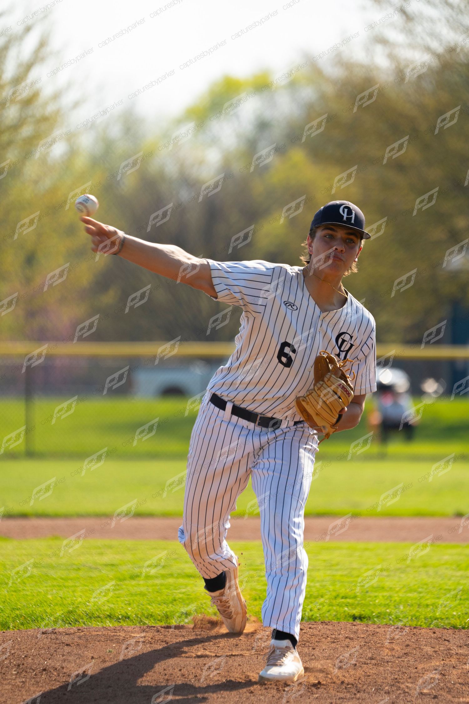 Baseball pitcher #6 in pinstripe uniform delivers pitch with full wind-up on sunny field.