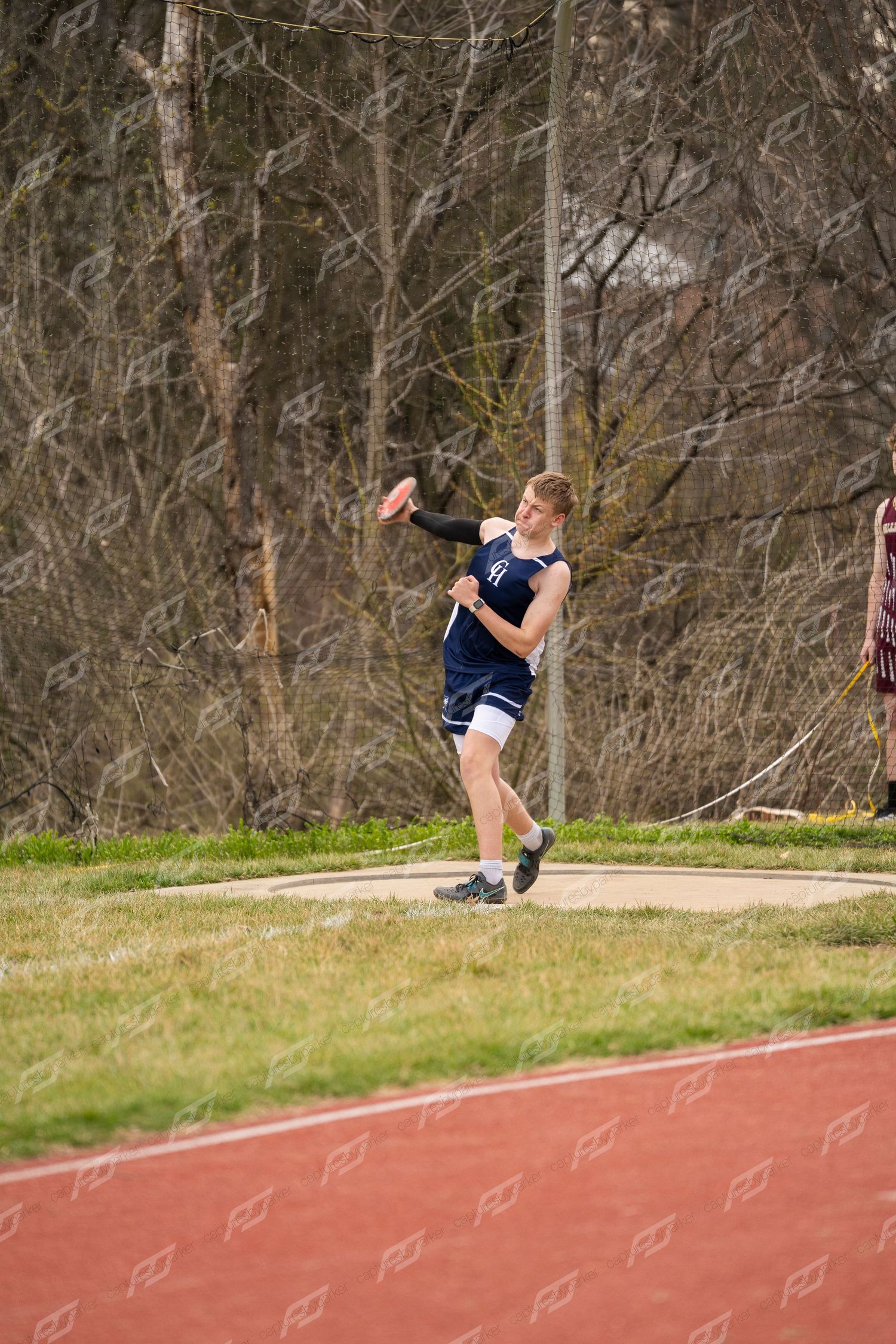 A male track athlete prepares to throw a discus during an outdoor high school track and field meet.