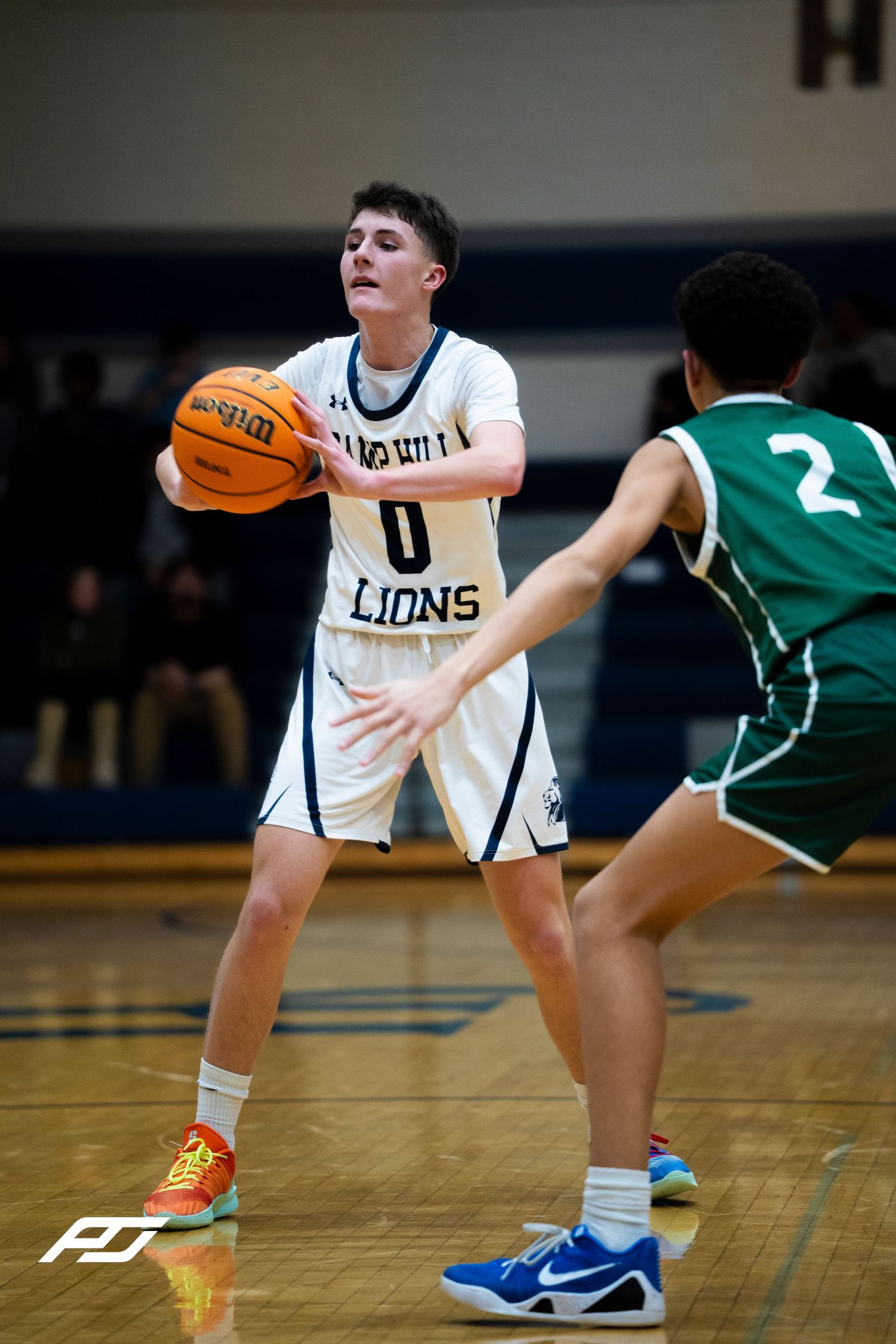 Camp Hill Lions #0 looks to pass while being guarded by opponent #2 in a basketball game.