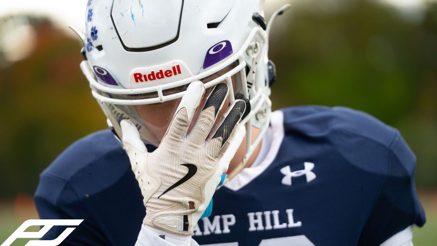 Close-up of football player in Riddell helmet and Camp Hill jersey on field.