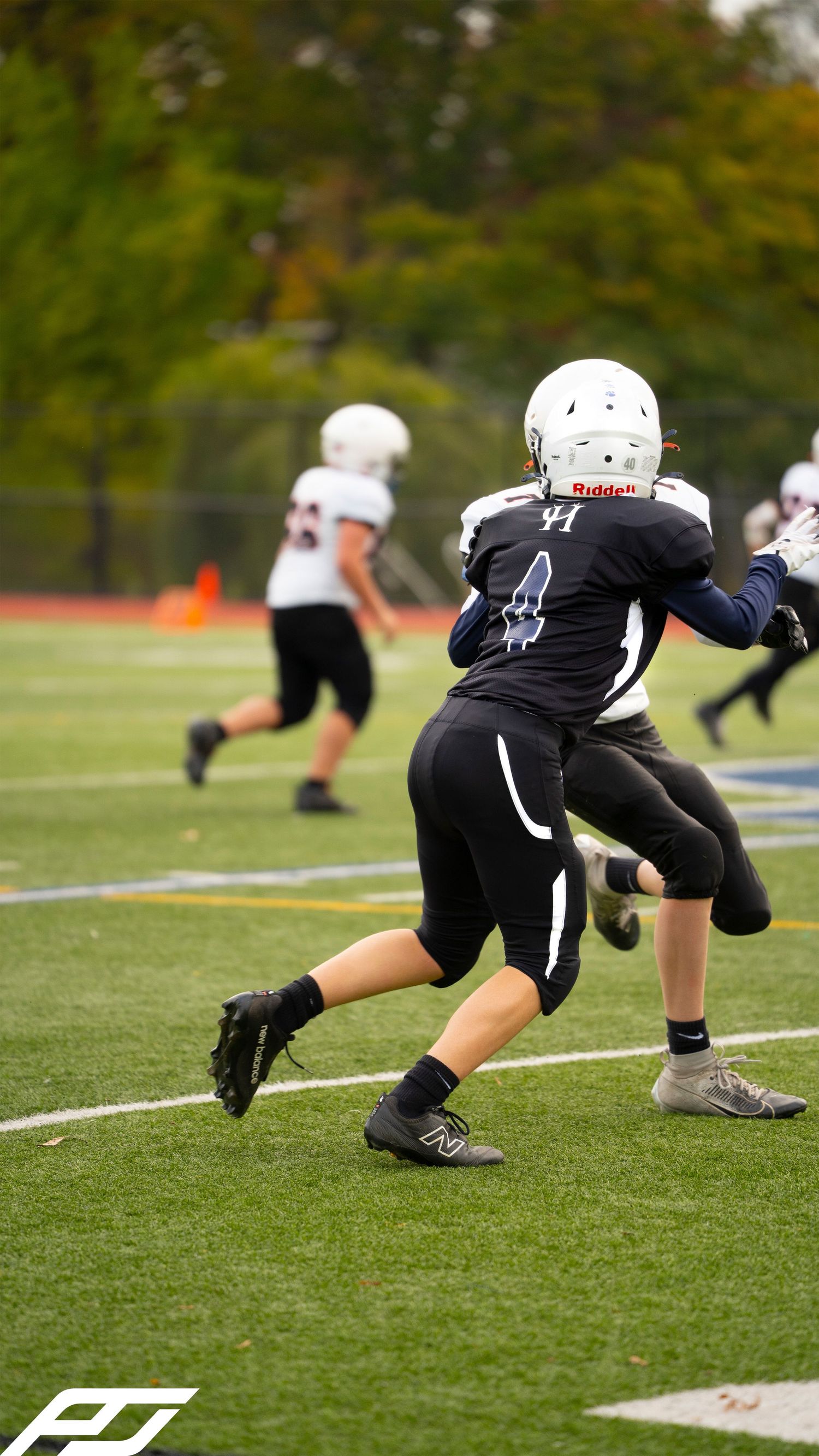 Youth football player #4 in black uniform makes a play on the field during a game.