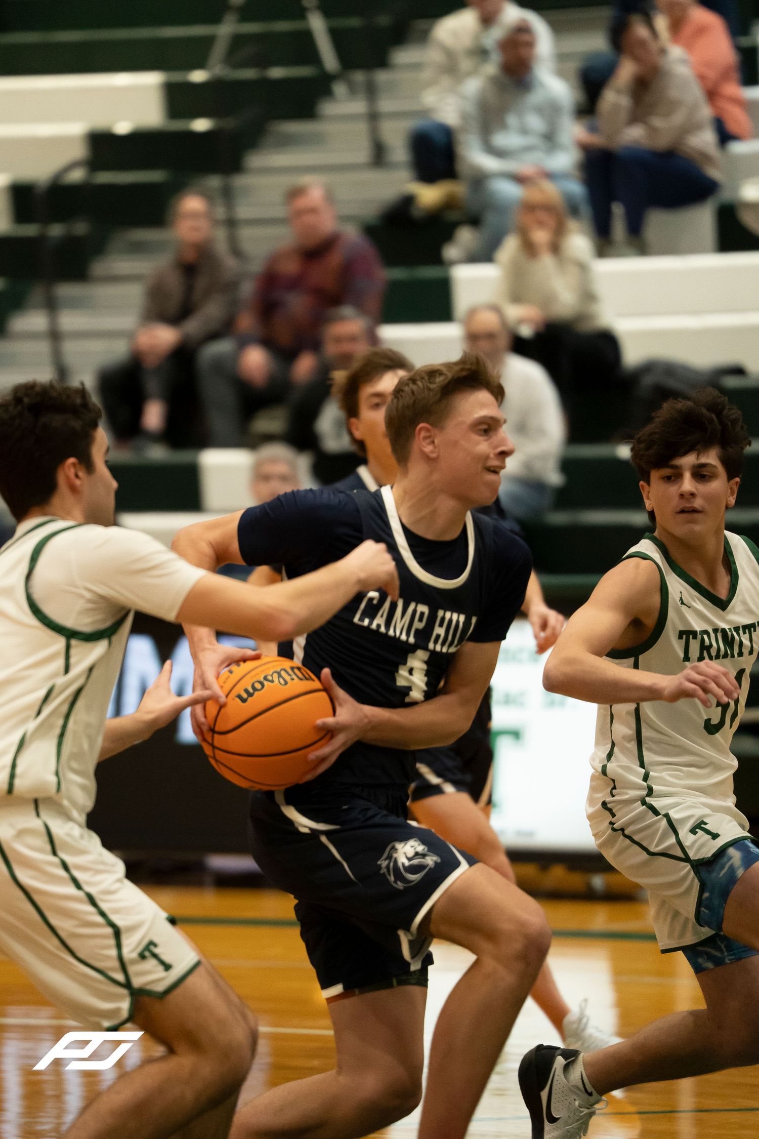 Camp Hill Lions number 4 drives through Trinity defenders during a high school basketball game.