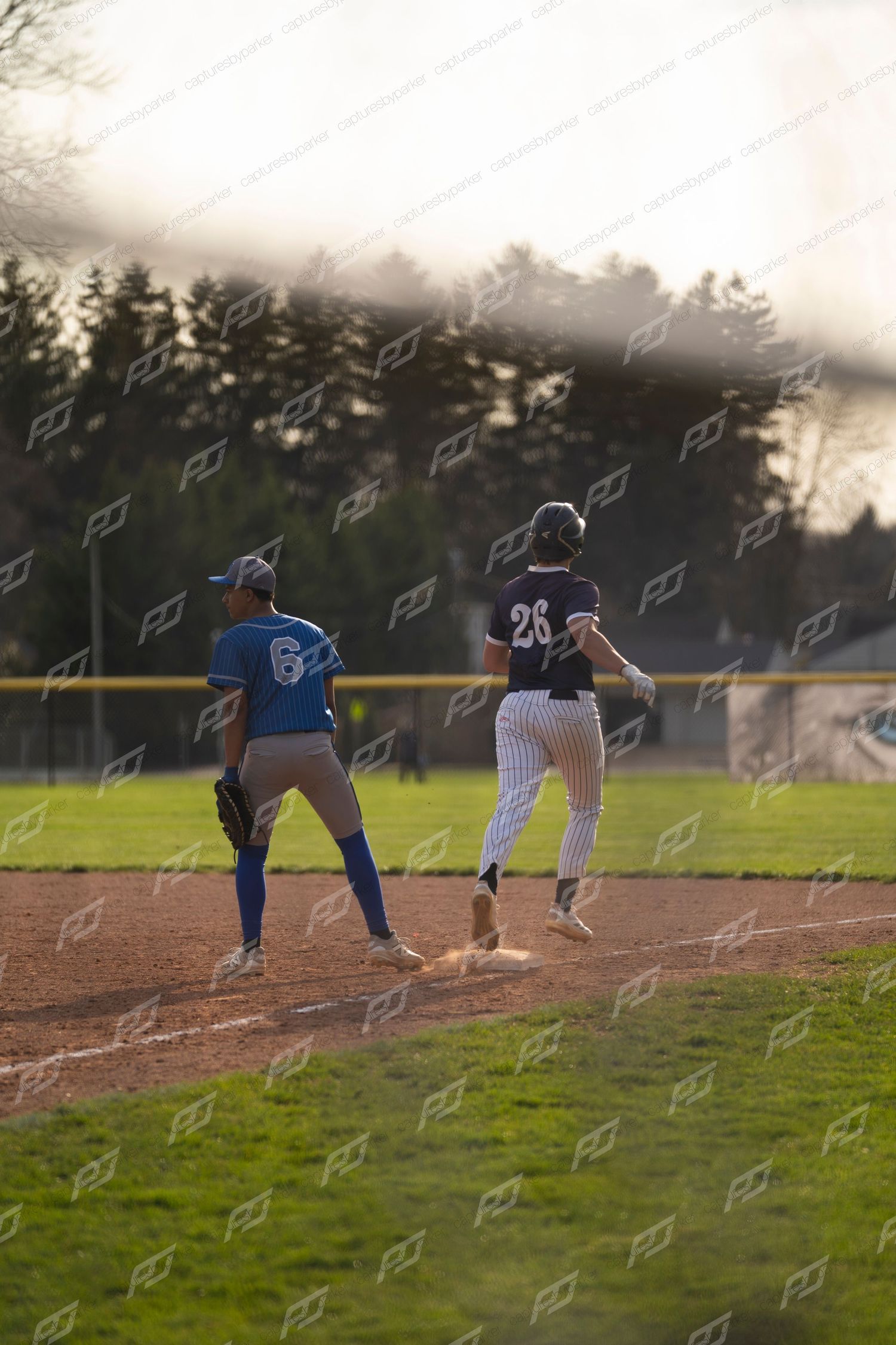 Baseball player #28 rounds second base as opposing player #6 in blue uniform watches during a game.