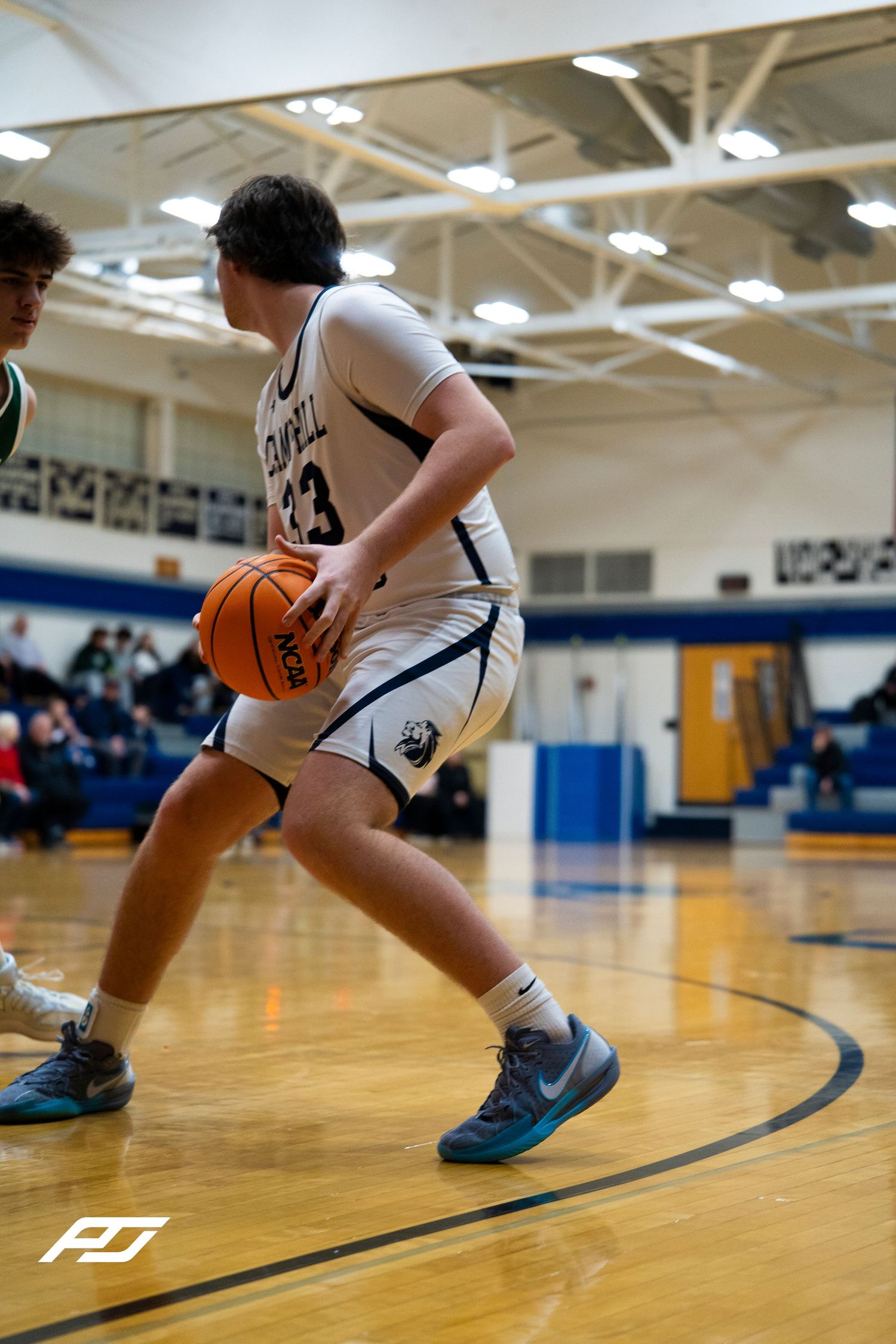 Camp Hill Lions #33 dribbles along the baseline during a high school basketball game.