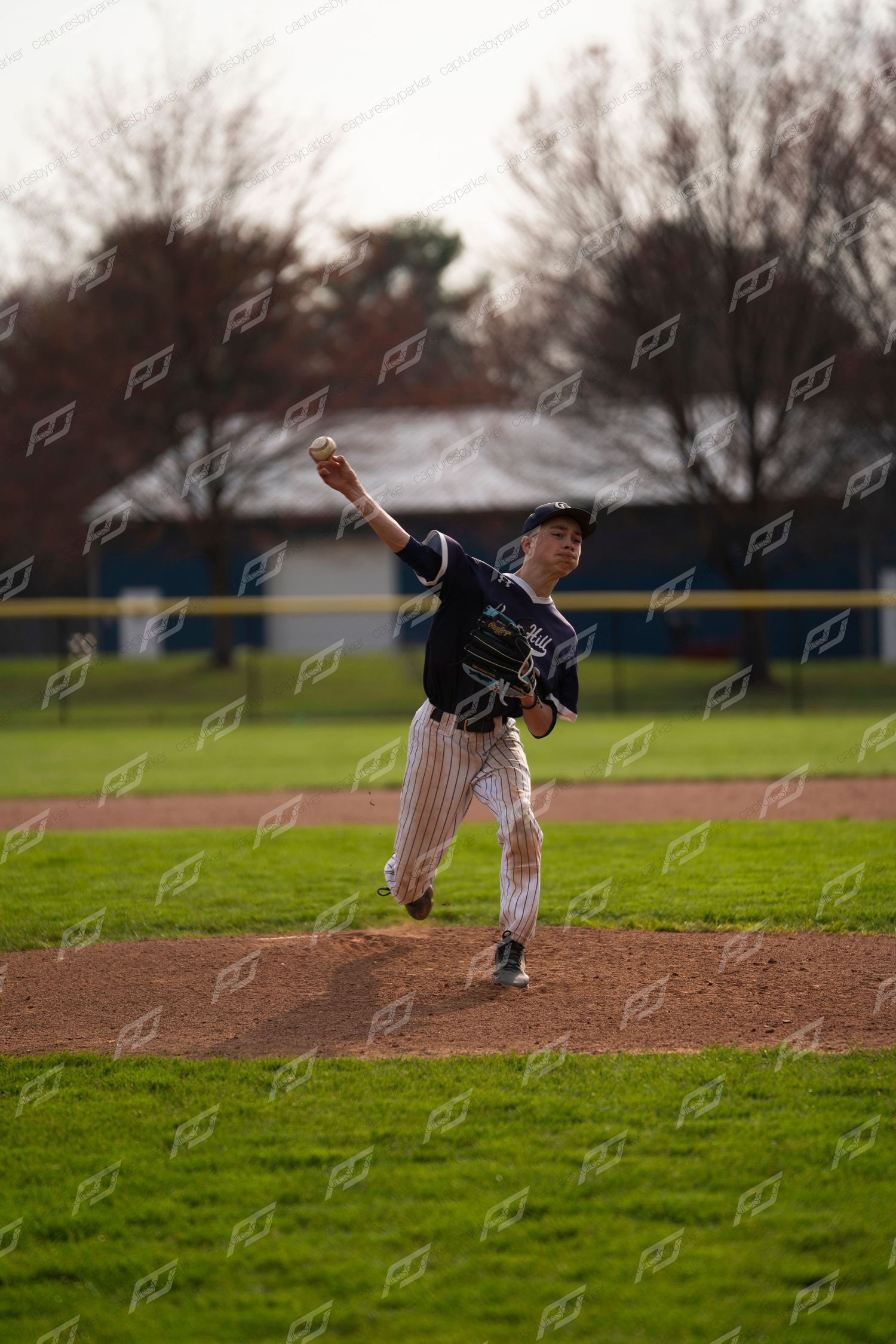 Baseball pitcher in navy pinstripe uniform winding up for a pitch on the mound.