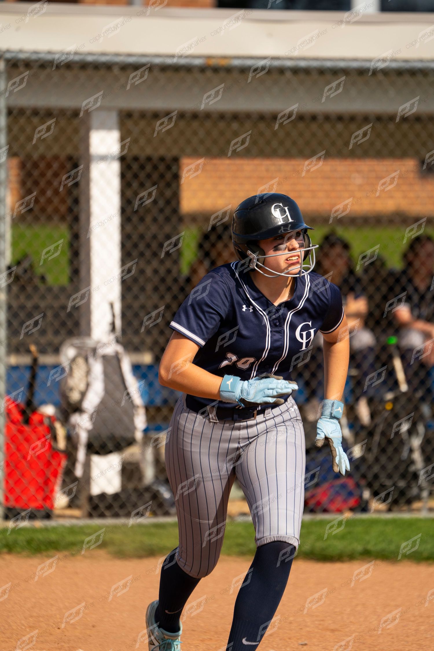 Female CH softball player in navy uniform runs the bases during a competitive game.