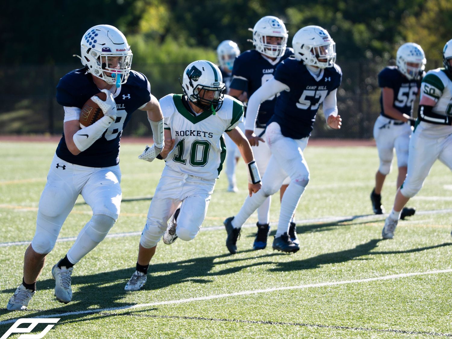 Youth football players in navy uniforms pursue a ball carrier during an exciting game.