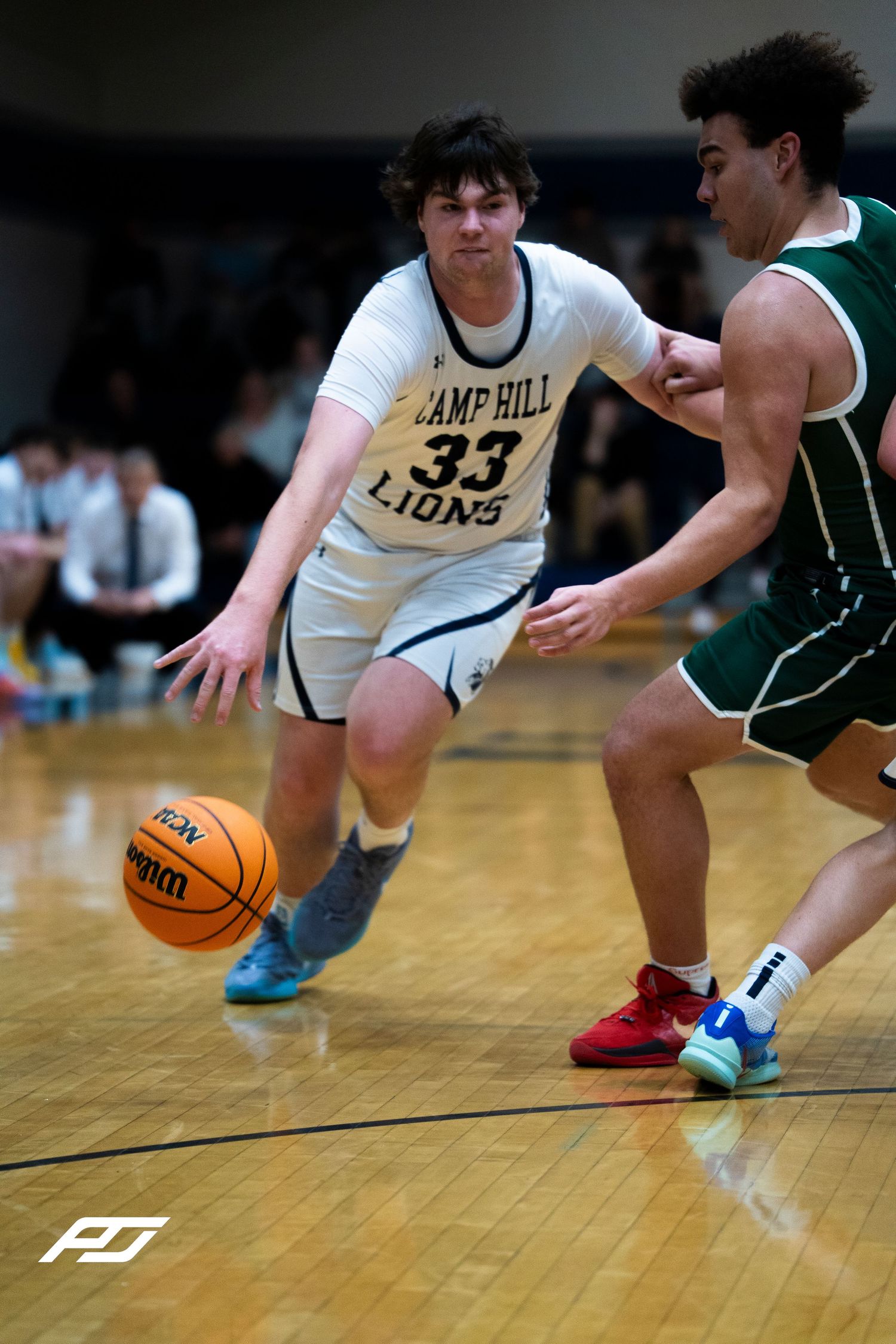 Camp Hill Lions number 33 drives baseline against a green-uniformed defender.
