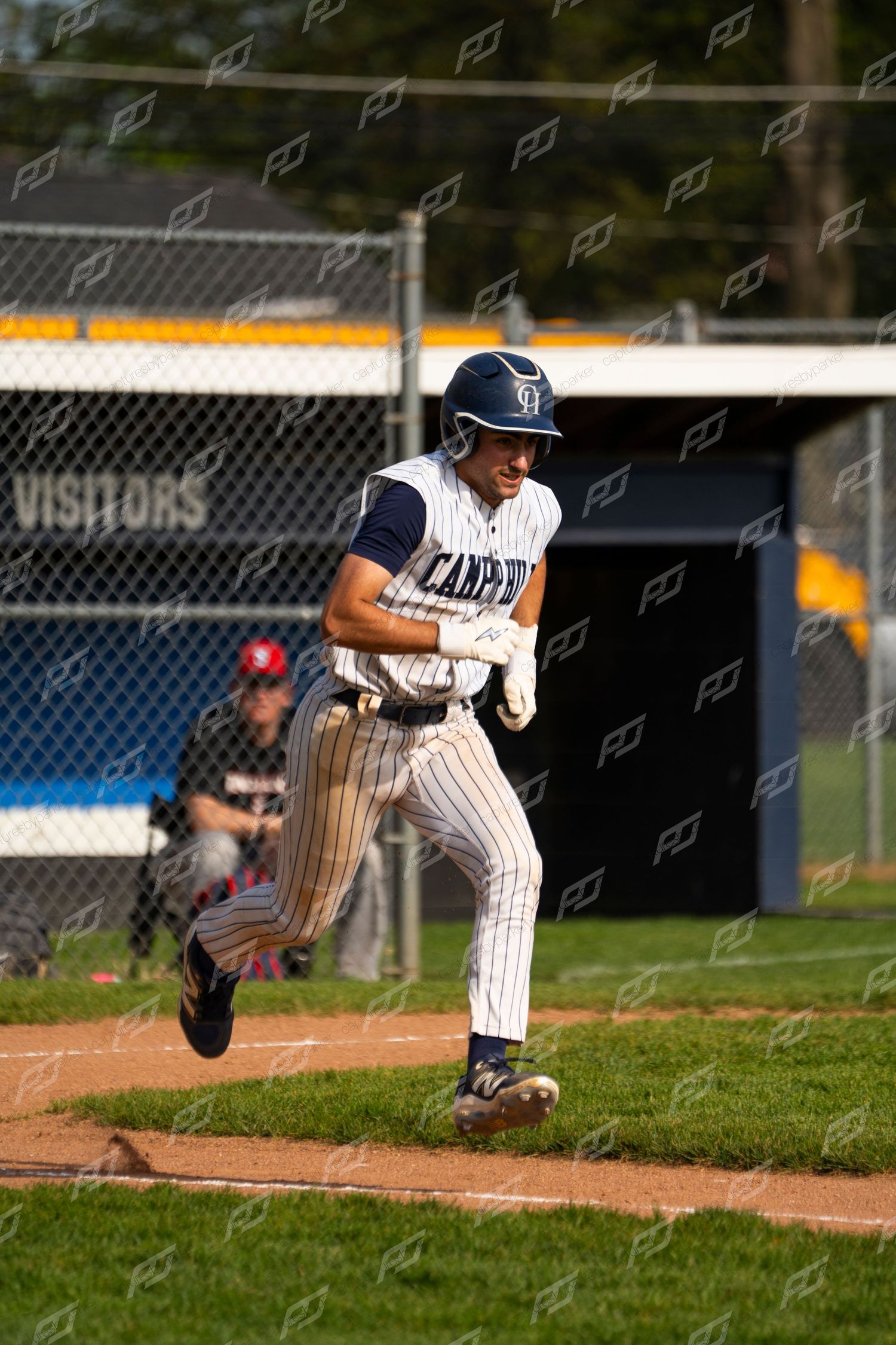 Baseball player in pinstripe uniform sprints from home plate past the visitors dugout sign.