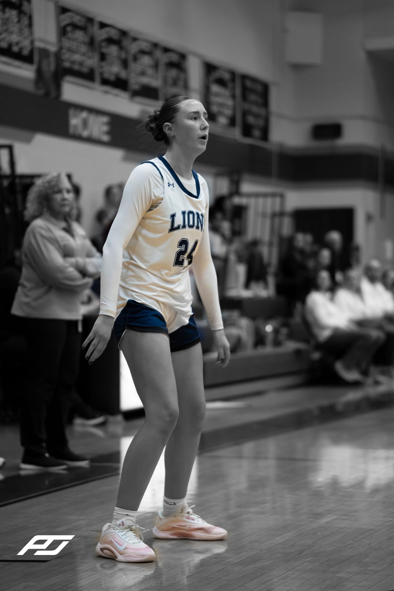 Lions number 24 stands on the court in a black and white action photo during a girls basketball game.