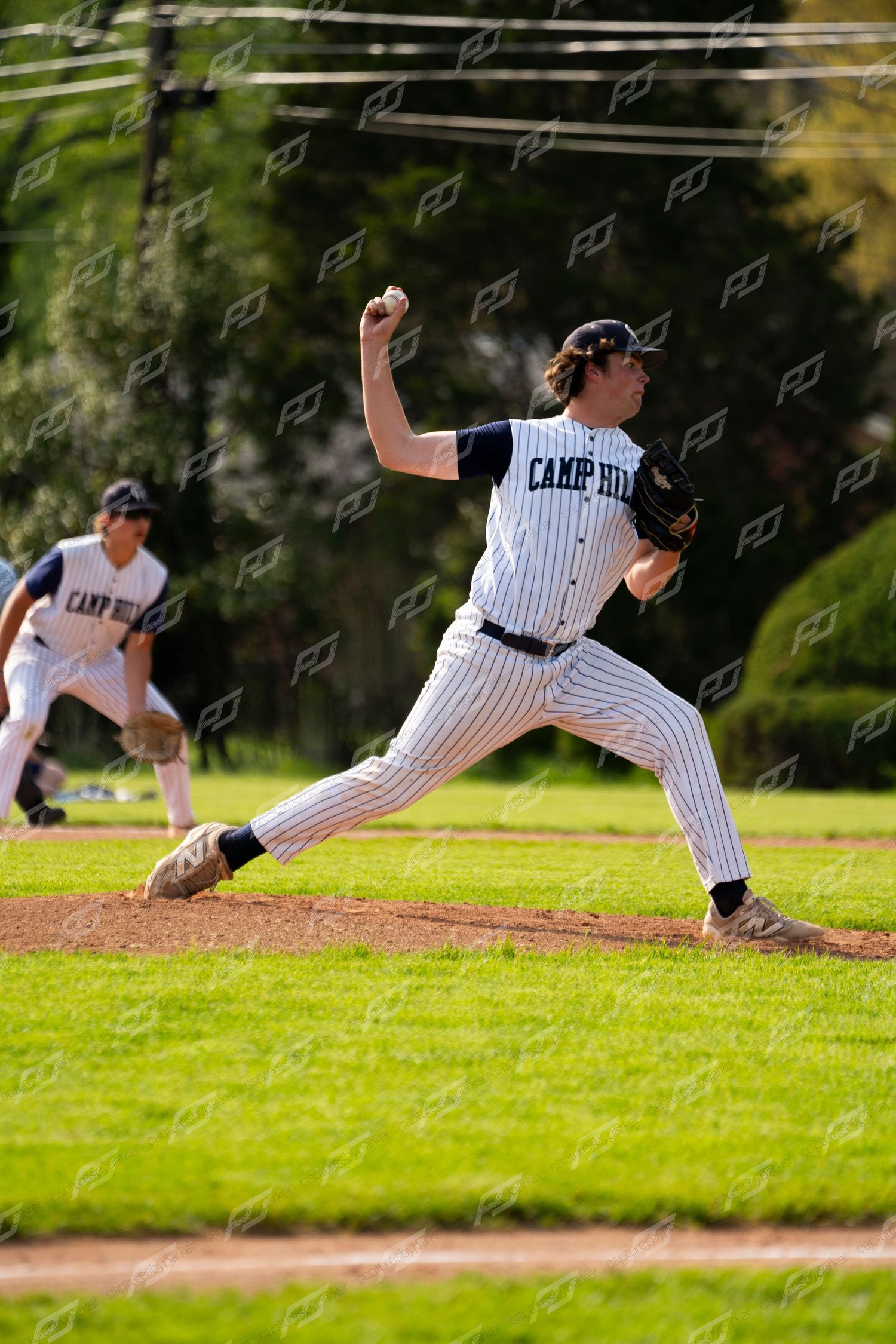 Camp Hill baseball pitcher delivers a pitch from the mound during a sunny outdoor game.