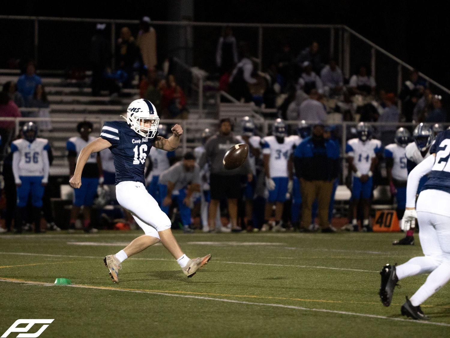 Camp Hill Lions player number 16 executes a kick during a night football game.