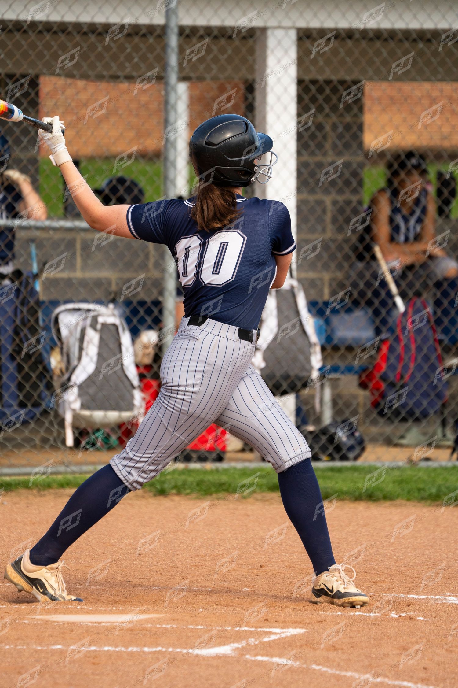 CH softball player number 00 follows through on a swing at home plate during a game.