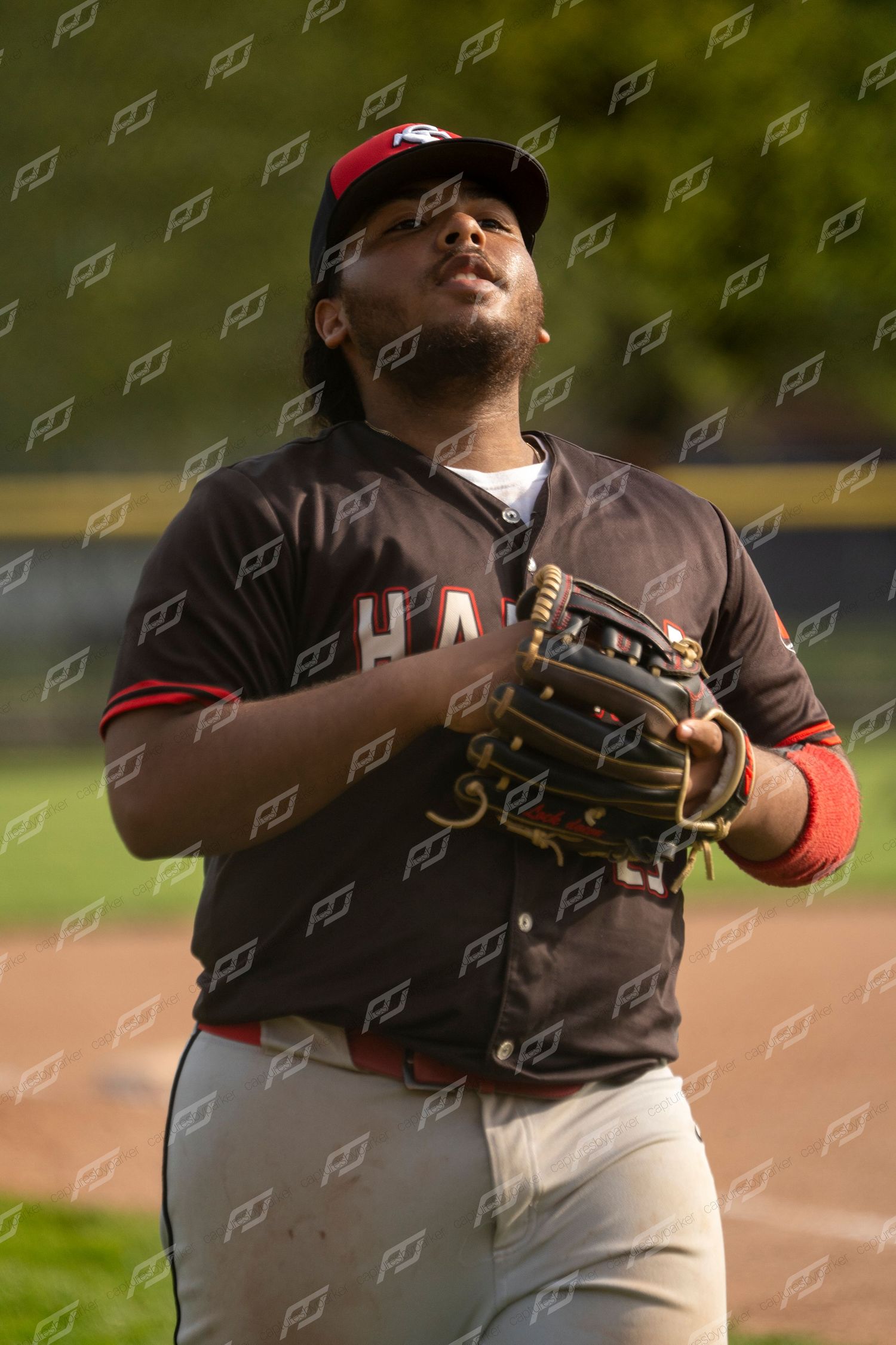 Hanna baseball outfielder in dark uniform looking up to track a fly ball while wearing a fielding glove.