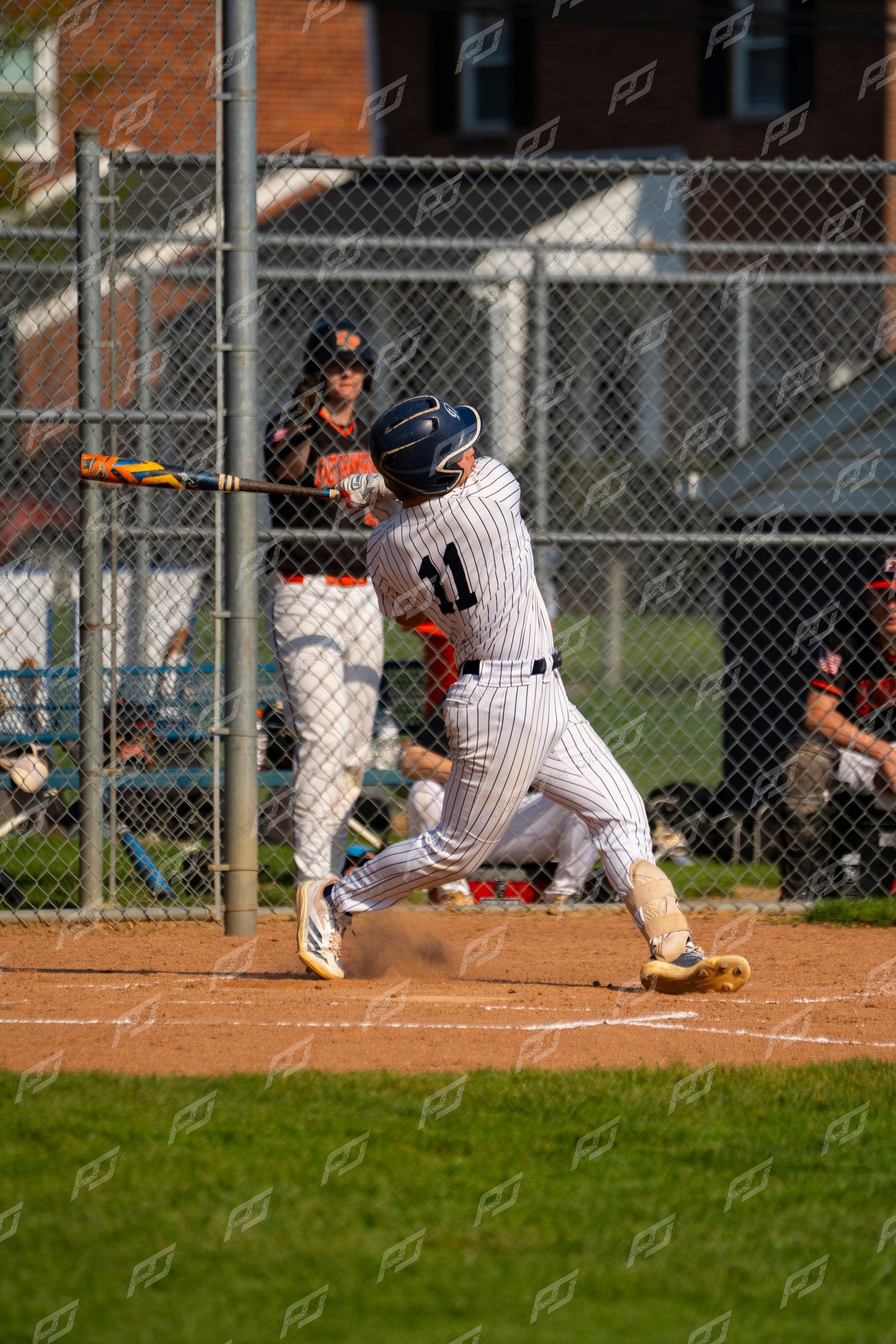 Baseball player #11 in pinstripe uniform makes contact with pitch at home plate.
