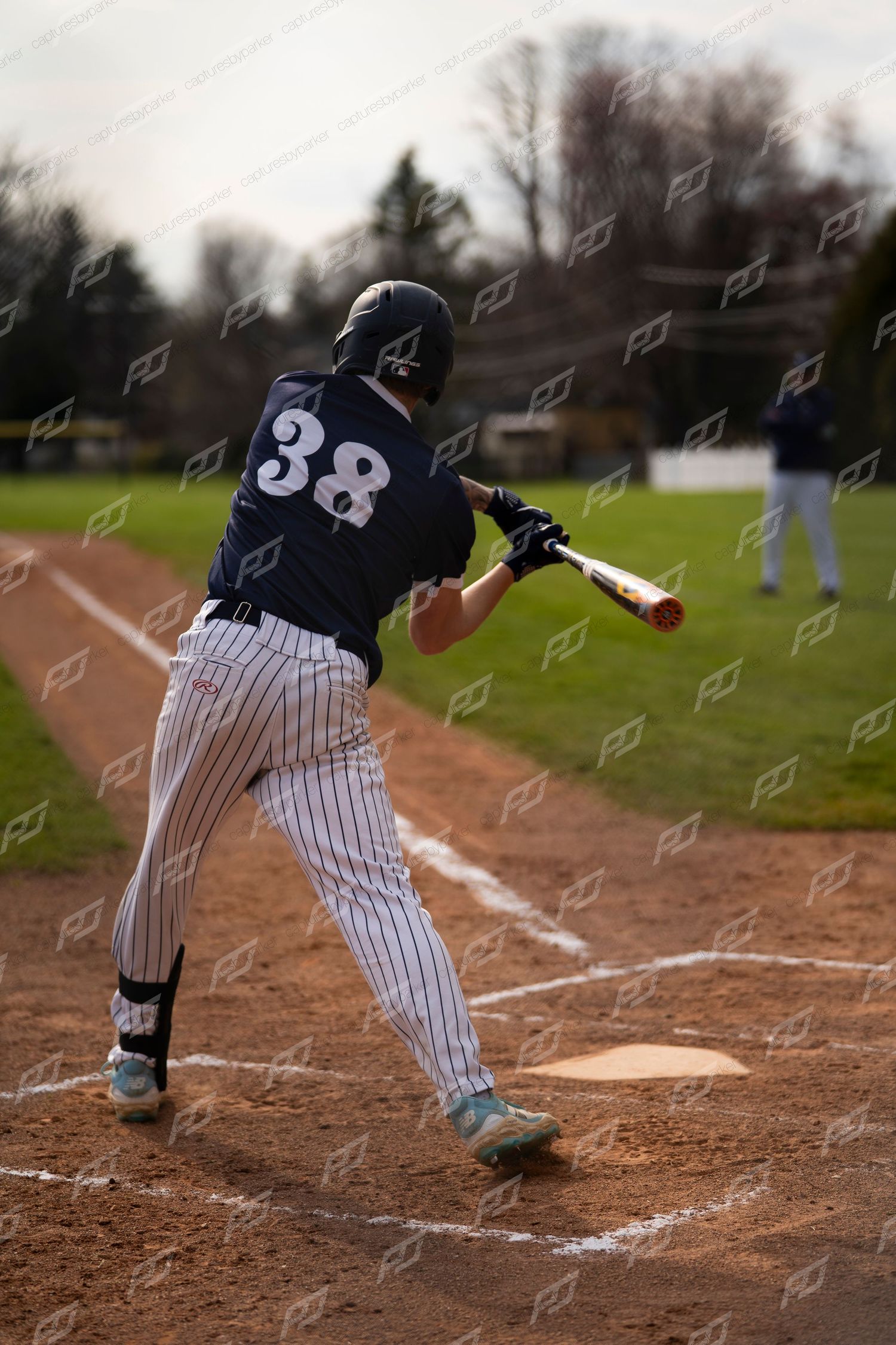 Baseball player #38 in navy pinstripe uniform takes a full swing at home plate.