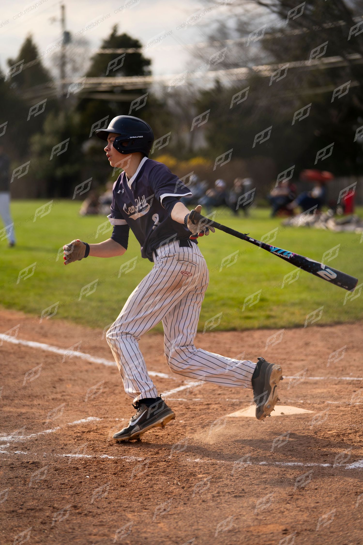 Baseball batter #2 in navy pinstripe uniform following through on a swing at home plate.