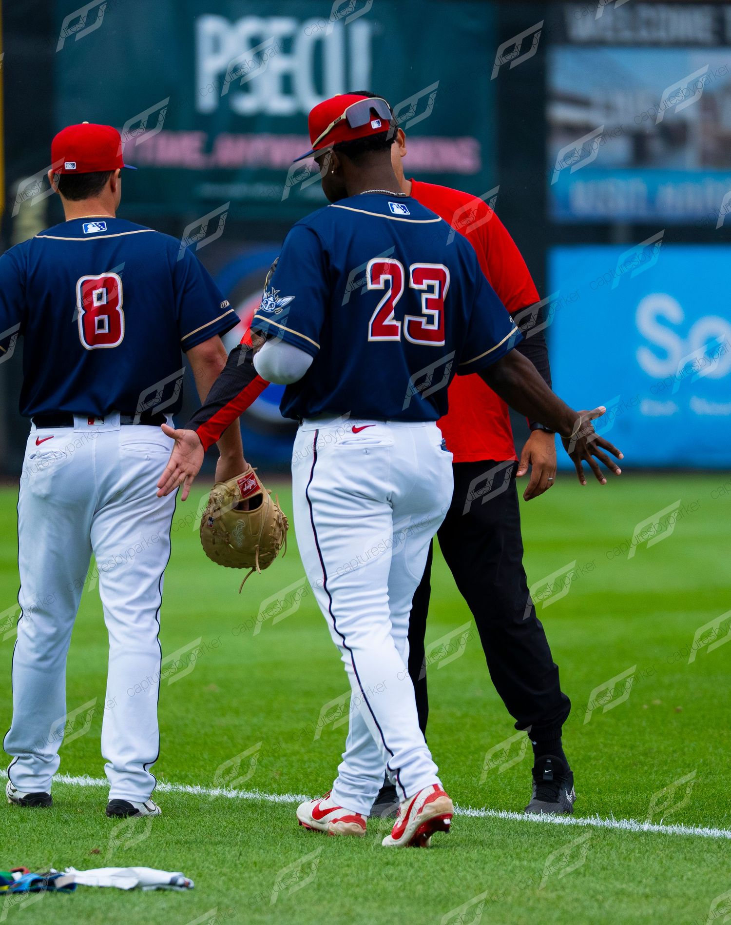Minor league baseball players in navy uniforms warm up on the field before a game.