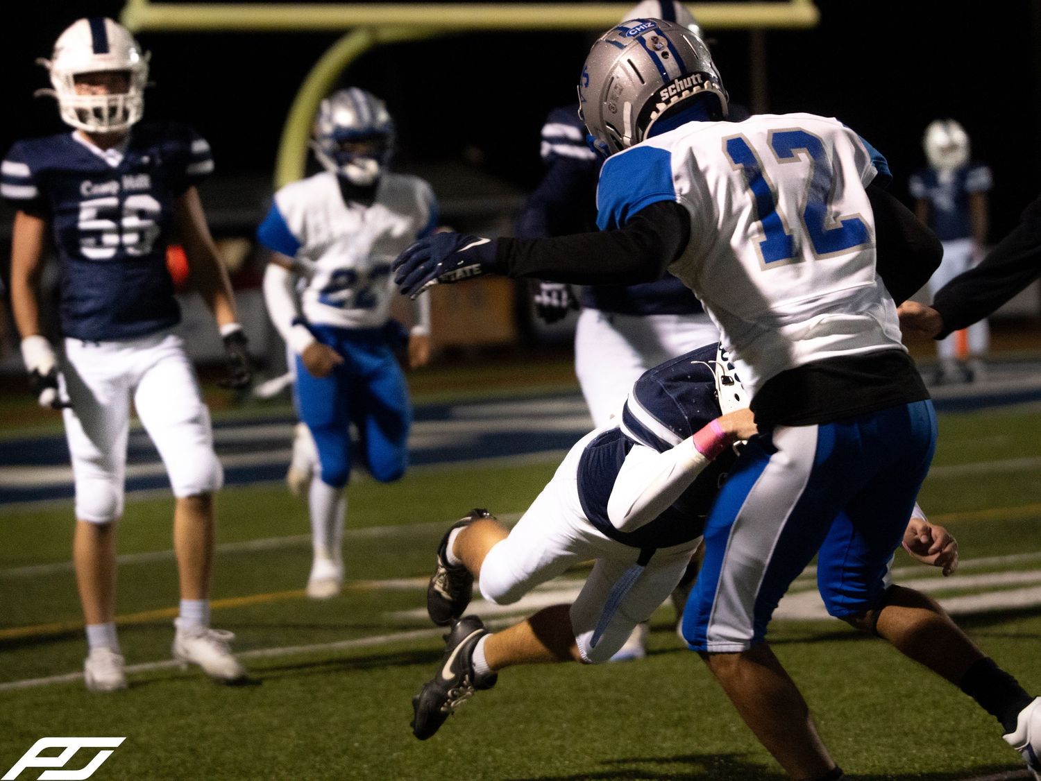 Football player number 12 in blue uniform makes dynamic play during night game.