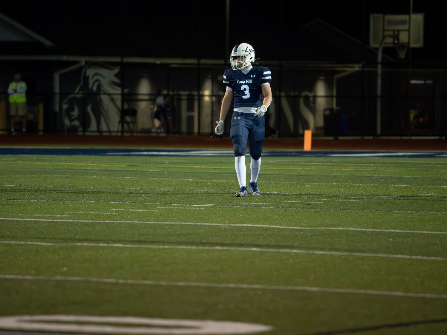 Camp Hill Lions football player number 3 stands alone on illuminated field during a night game.