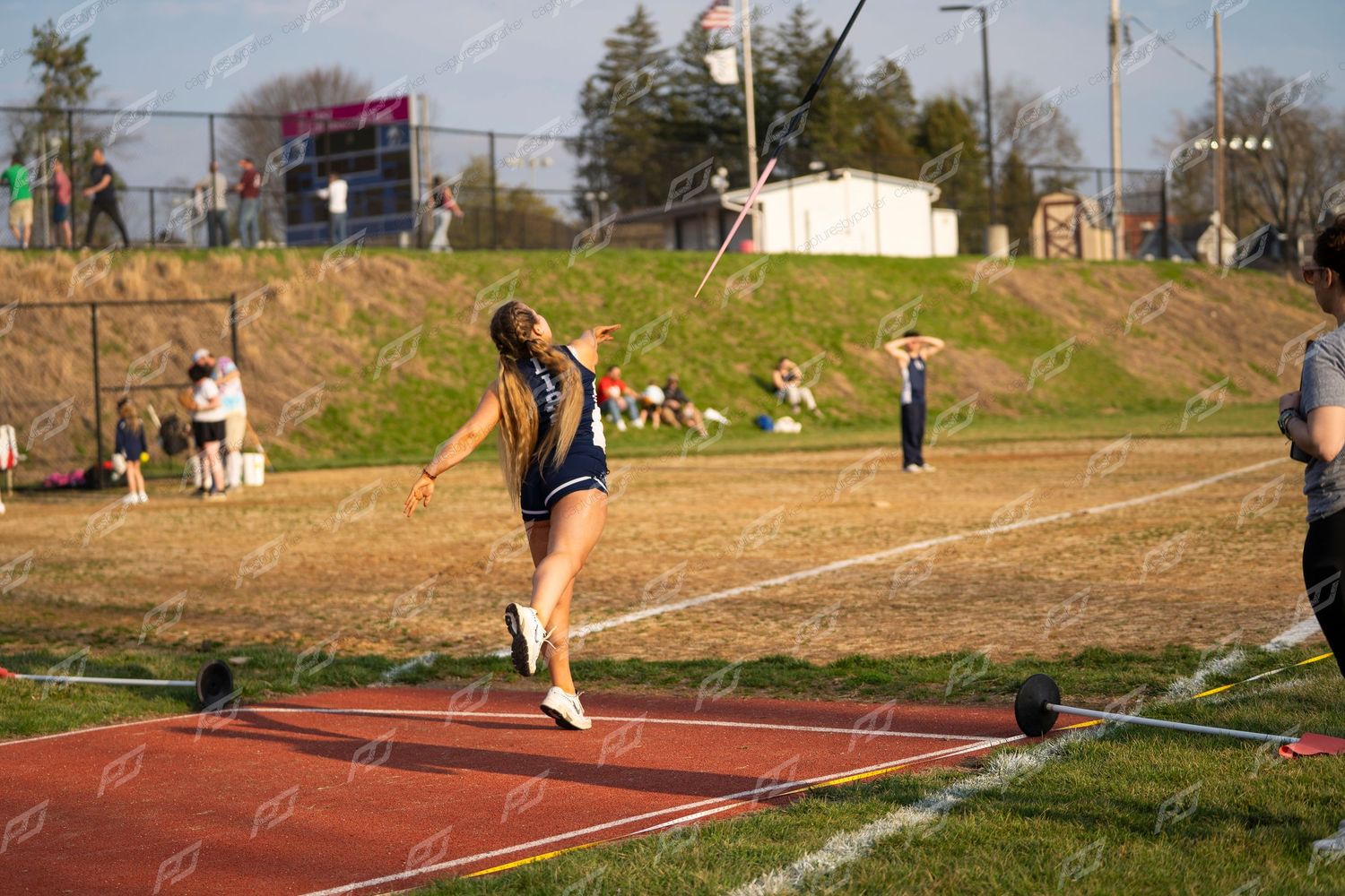 Female athlete throwing javelin at outdoor track meet.