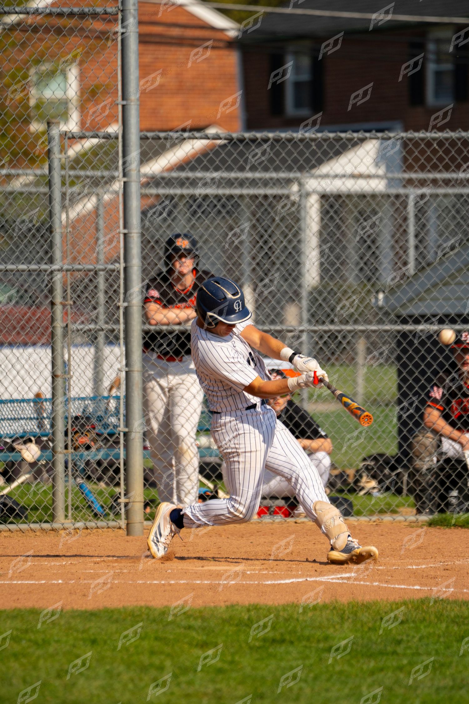 Baseball batter in pinstripe uniform follows through on powerful swing at home plate.