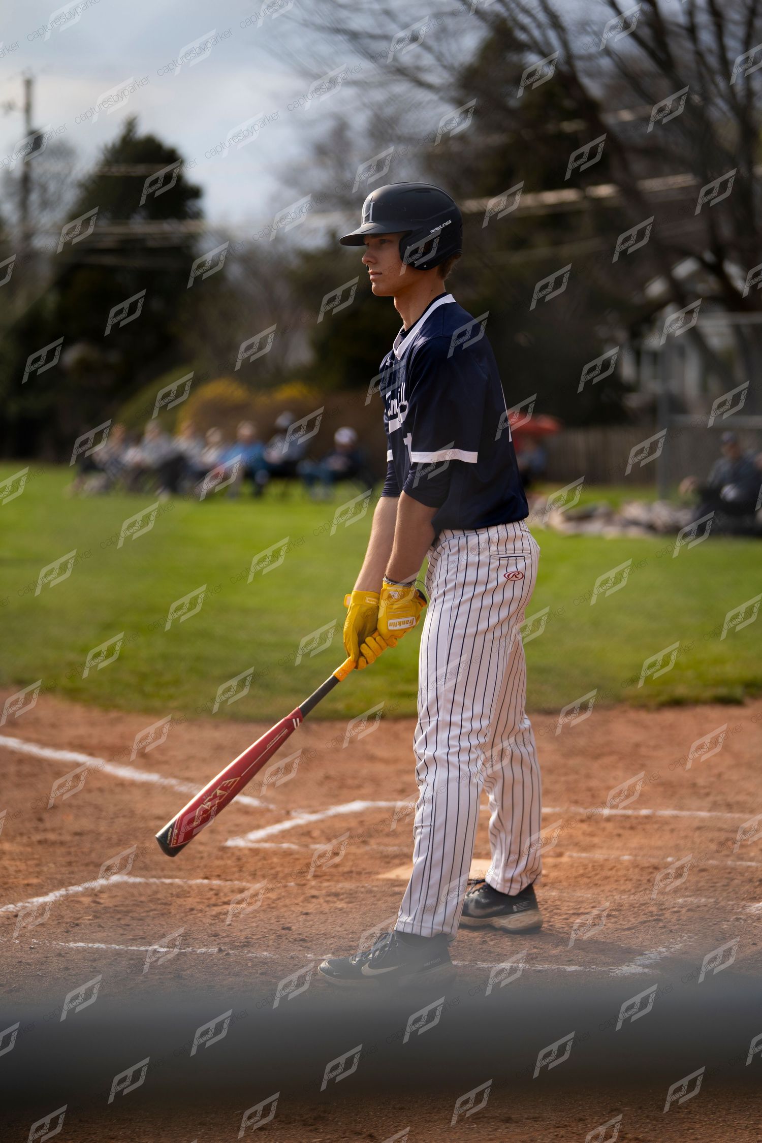 Baseball player in navy uniform stands at home plate holding bat ready to hit.