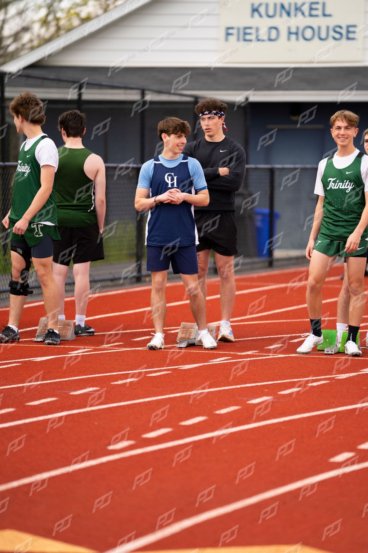 CH and Trinity high school track athletes socialize on red track near Kunkel Field House between events.